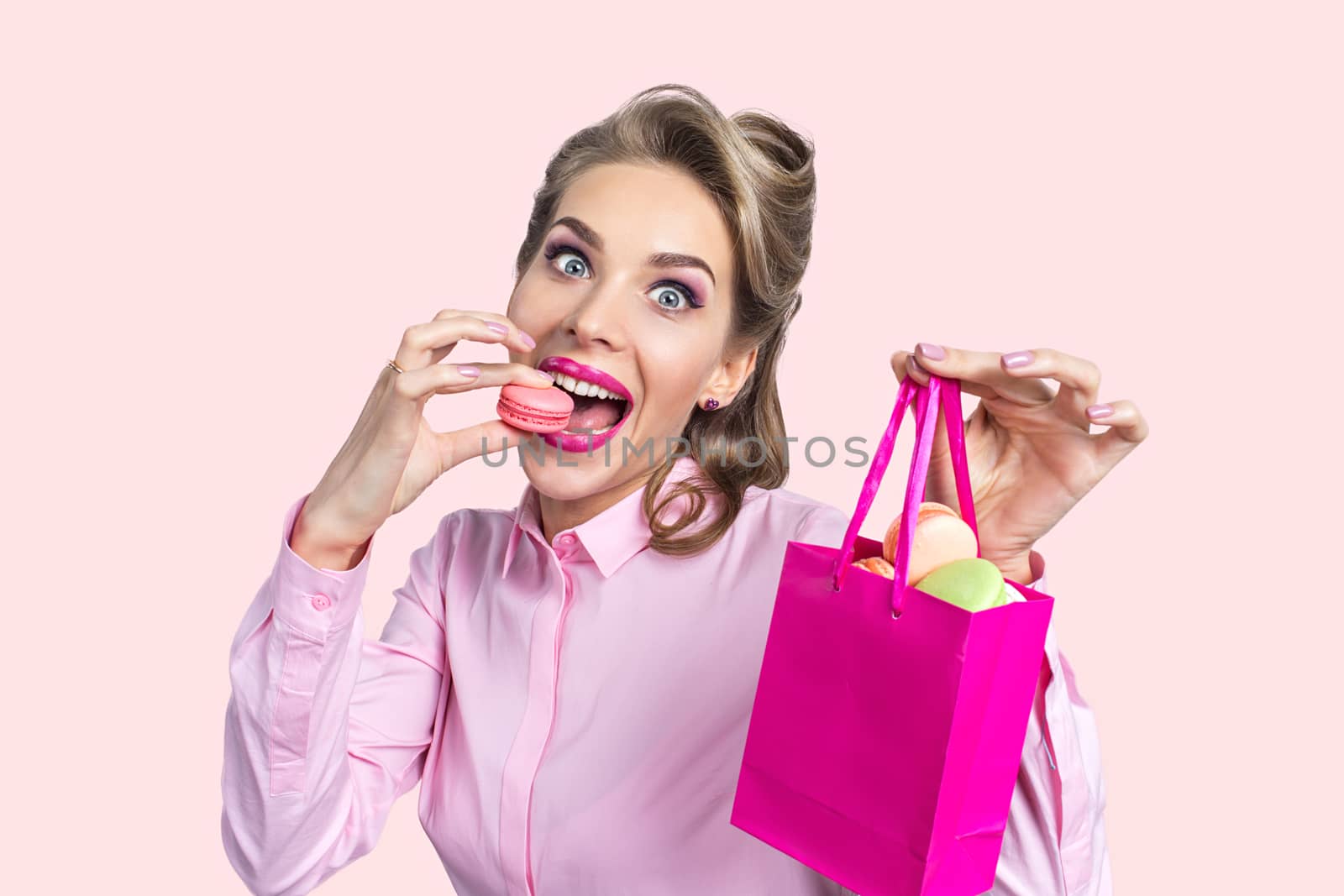 Funny smiling blond woman eating three macaroons