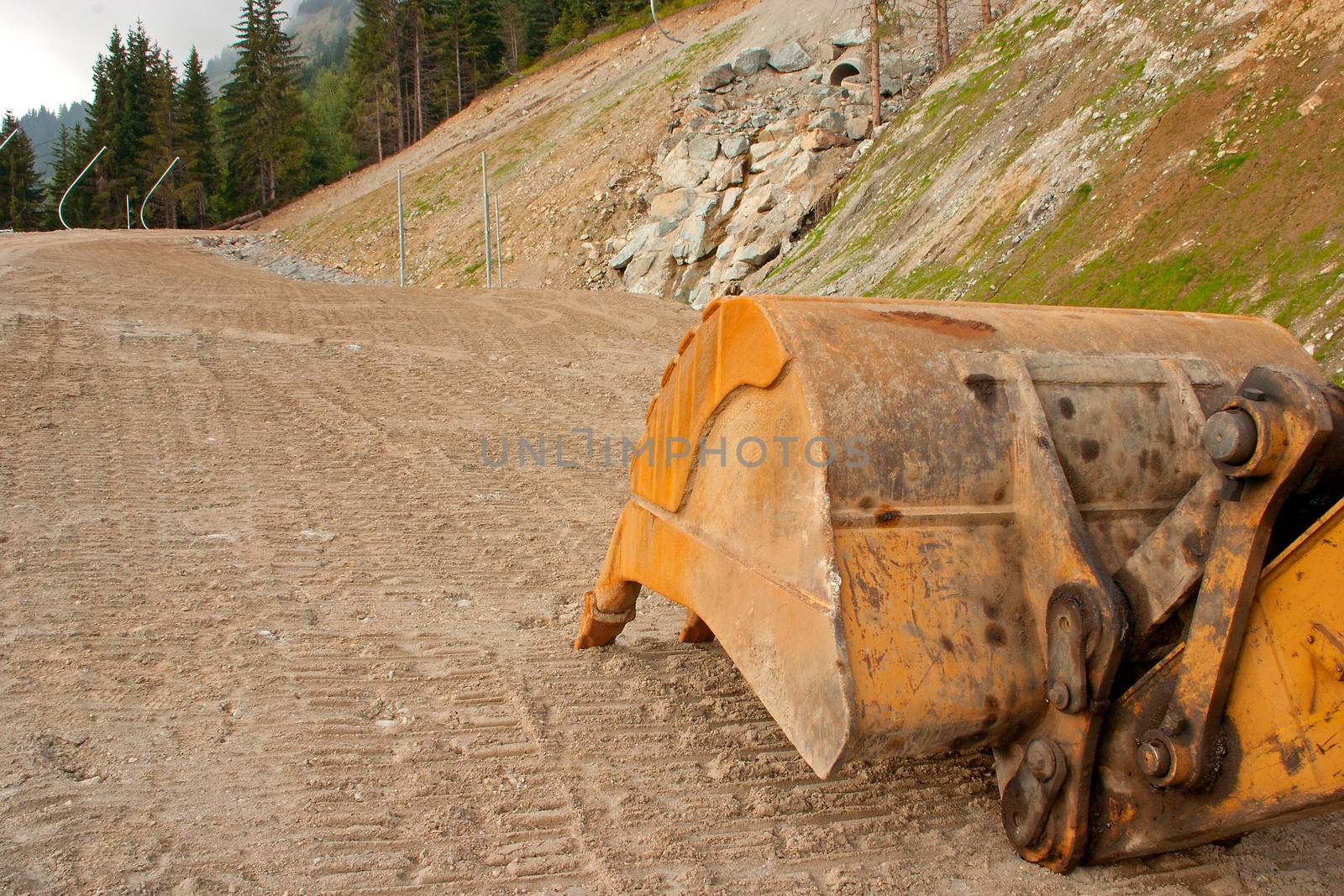 A yellow digger or excavator used to prepare a new track in the mountains