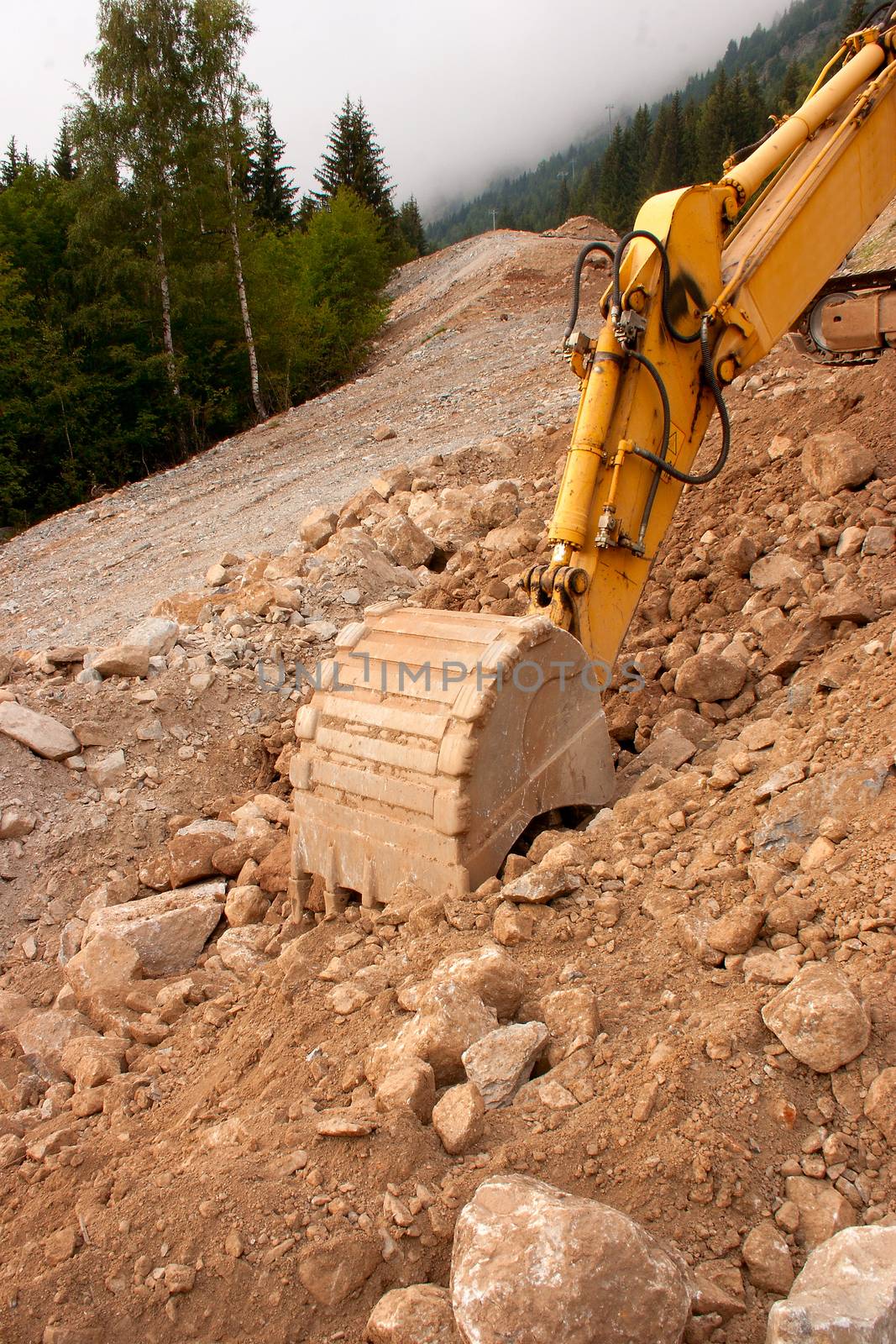 A yellow digger or excavator used to prepare a new track in the mountains