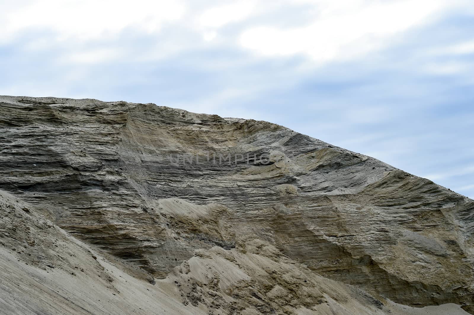 Sandy hill in a quarry against the sky.
