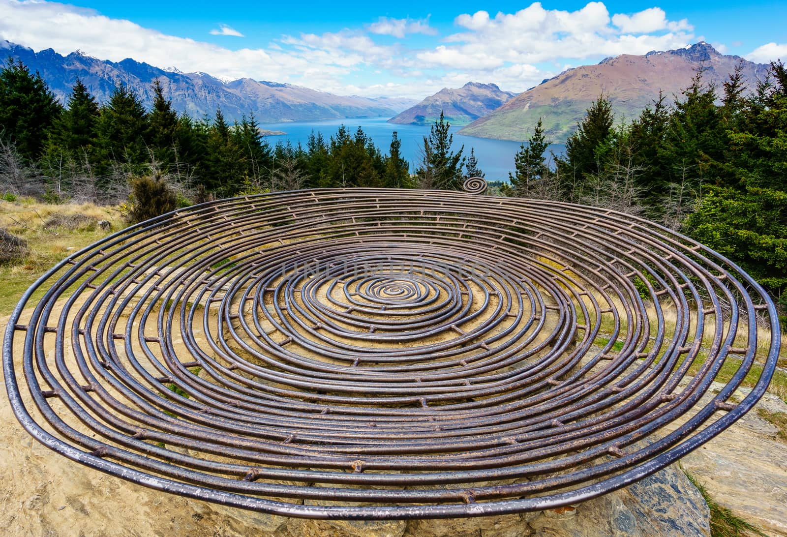 Metallic concentric circle sculpture. Basket of dreams. View point looking out over lake and mountains. Queens town, New Zealand.