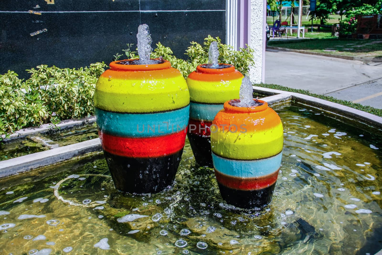 colorful jar pot fountain in pond front of entrance door
