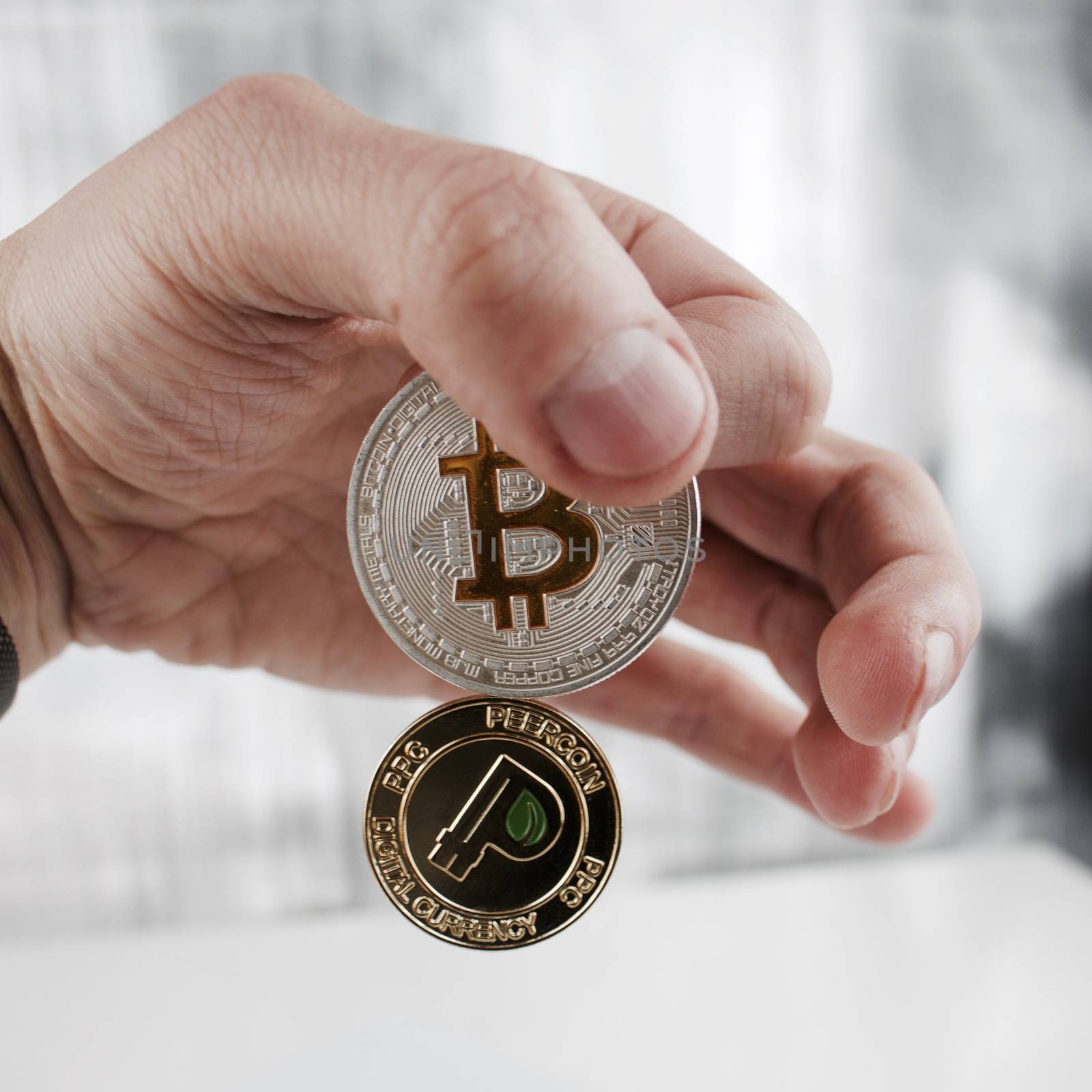 Digital currency physical silver bitcoin and gold peercoin in hand.