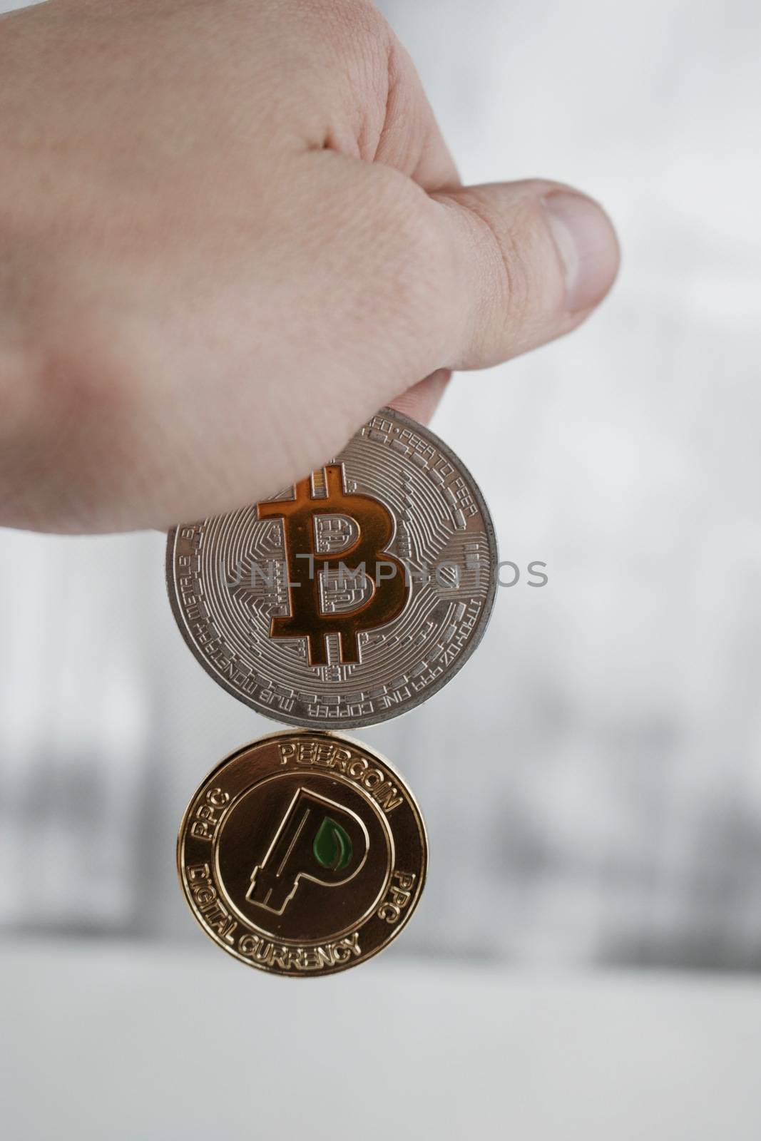 Cryptocurrency physical silver bitcoin and gold peercoin in hand.