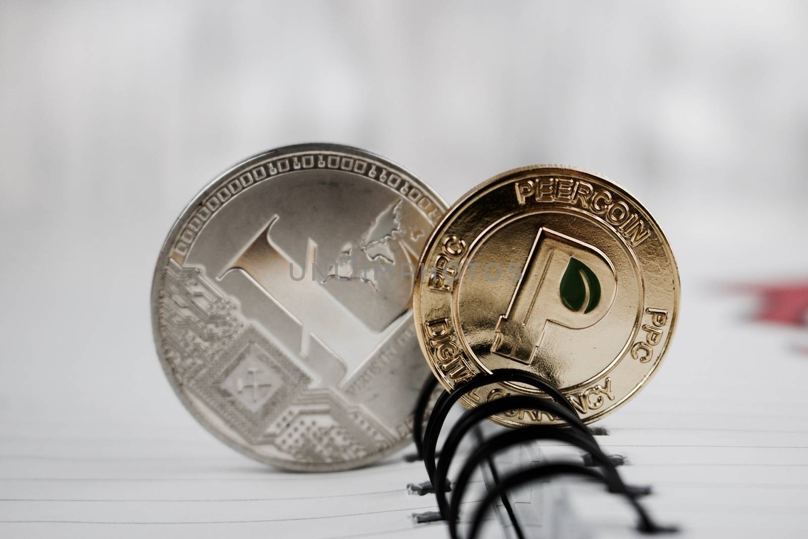 Digital currency physical gold peercoin and silver litecoin in notebook.
