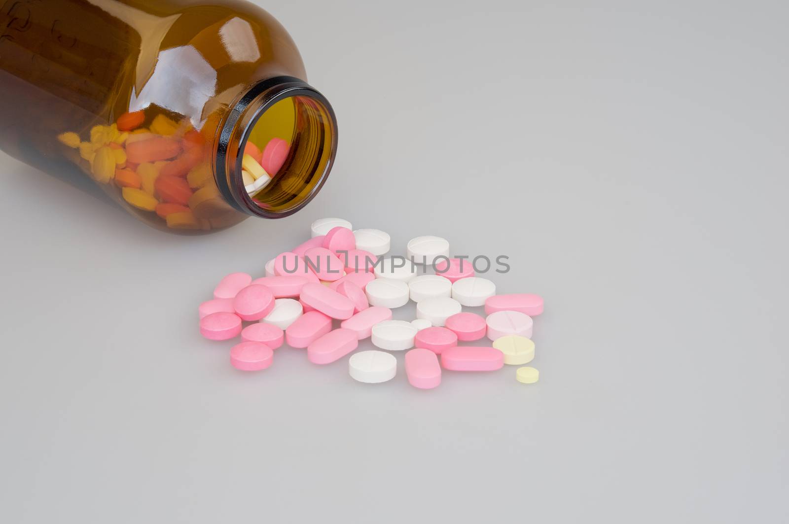 Colorful tablets and brown bottle place on a white background.