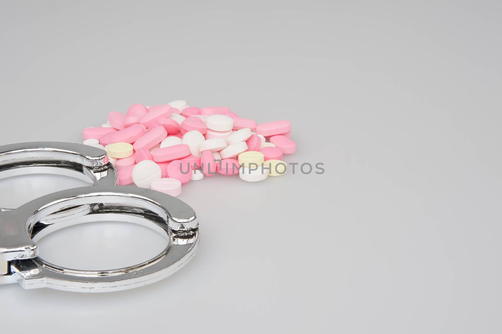 Silver handcuffs and stack of tablets on white background by eaglesky