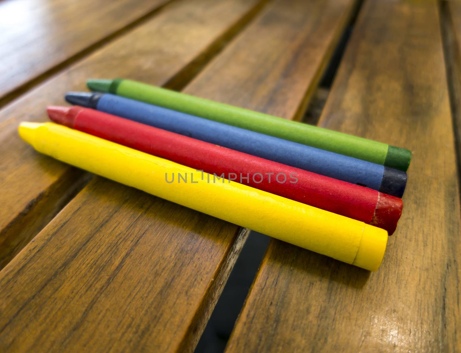 This is an image of a set of coloring crayons aranged on a wooden table.  They are aranged by primary colors.