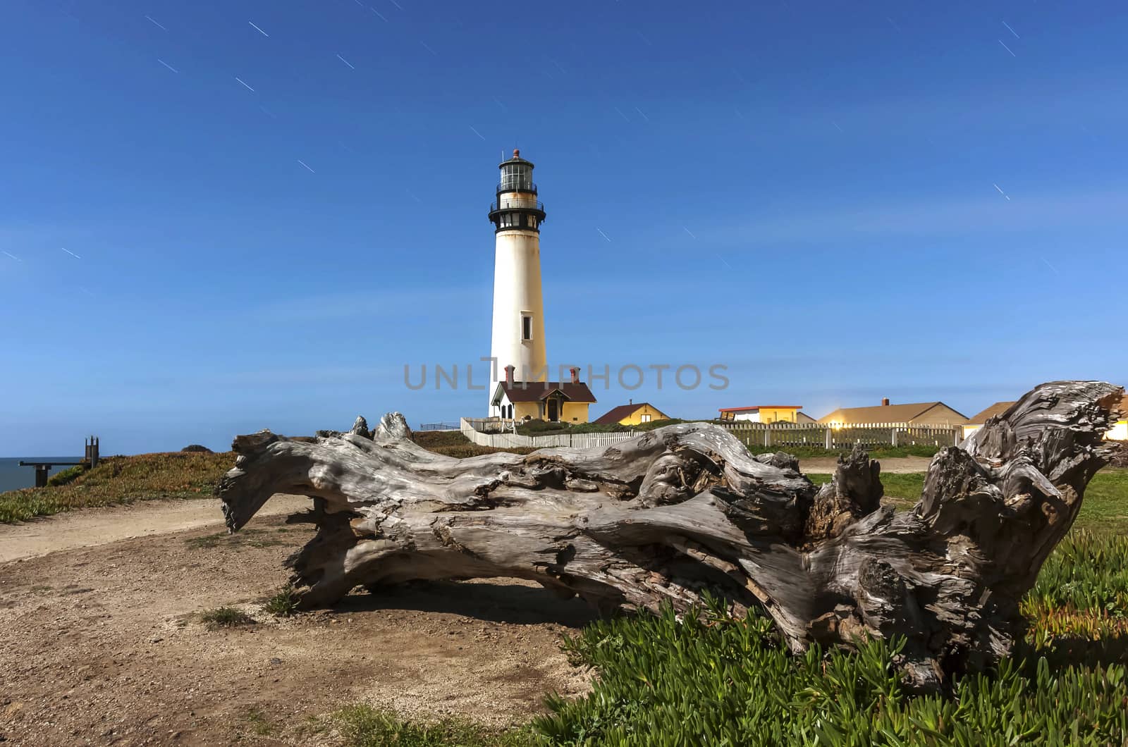 Pigeon Point Lighthouse. Located in Pescadero, California. Image is a long exposure shot of the lighthouse and log set in a trail of stars.