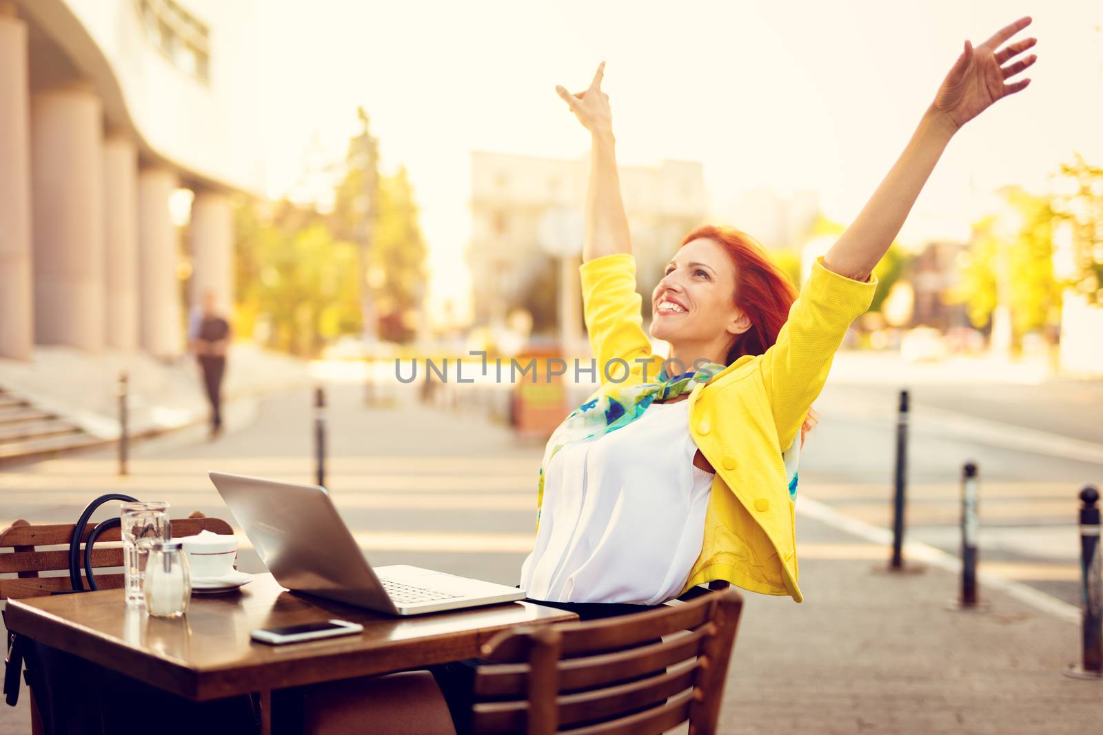 Successful businesswoman with outstretched arms on a coffee break in a street cafe.