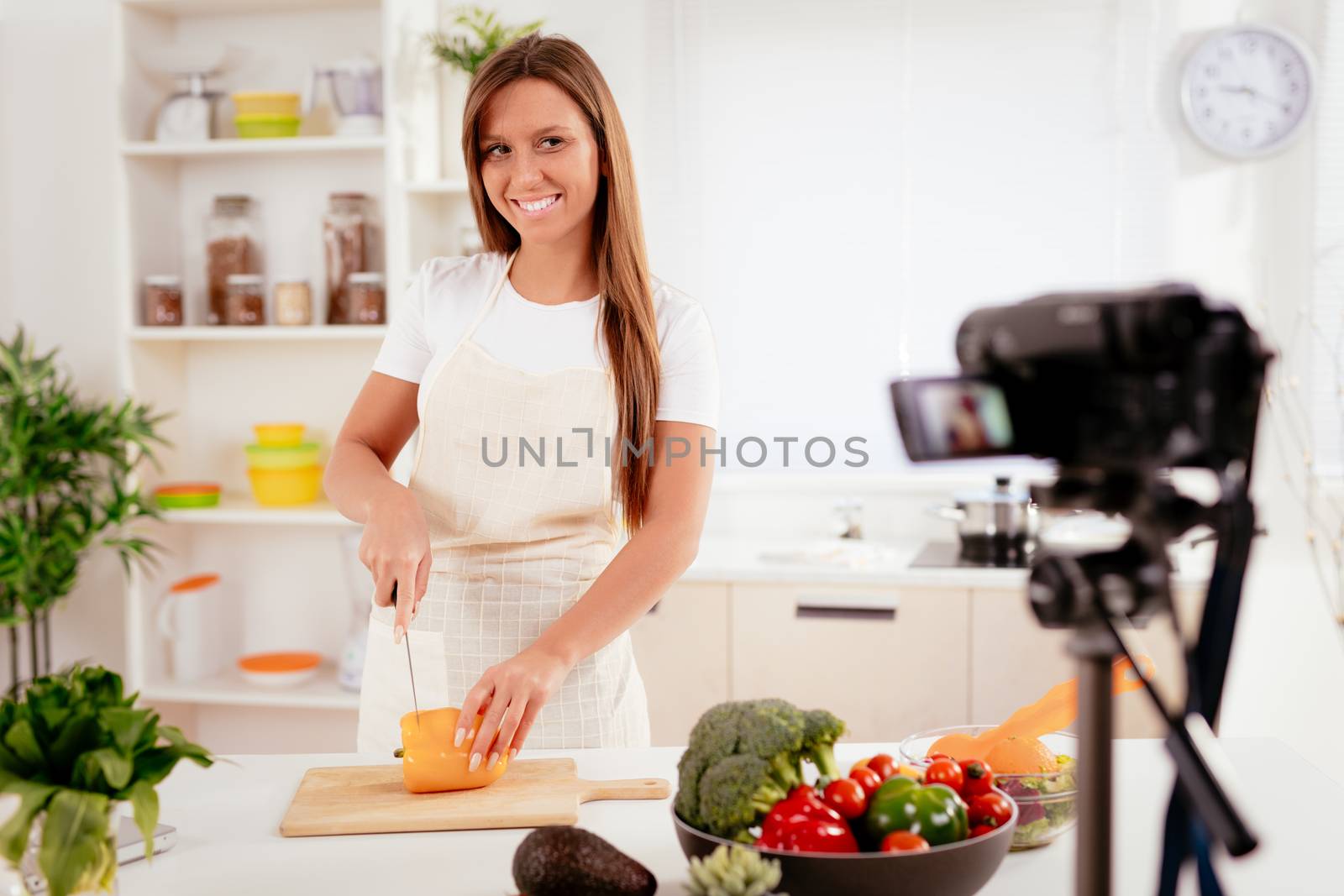 Beautiful young woman filming her blog broadcast about healthy food at the home.
