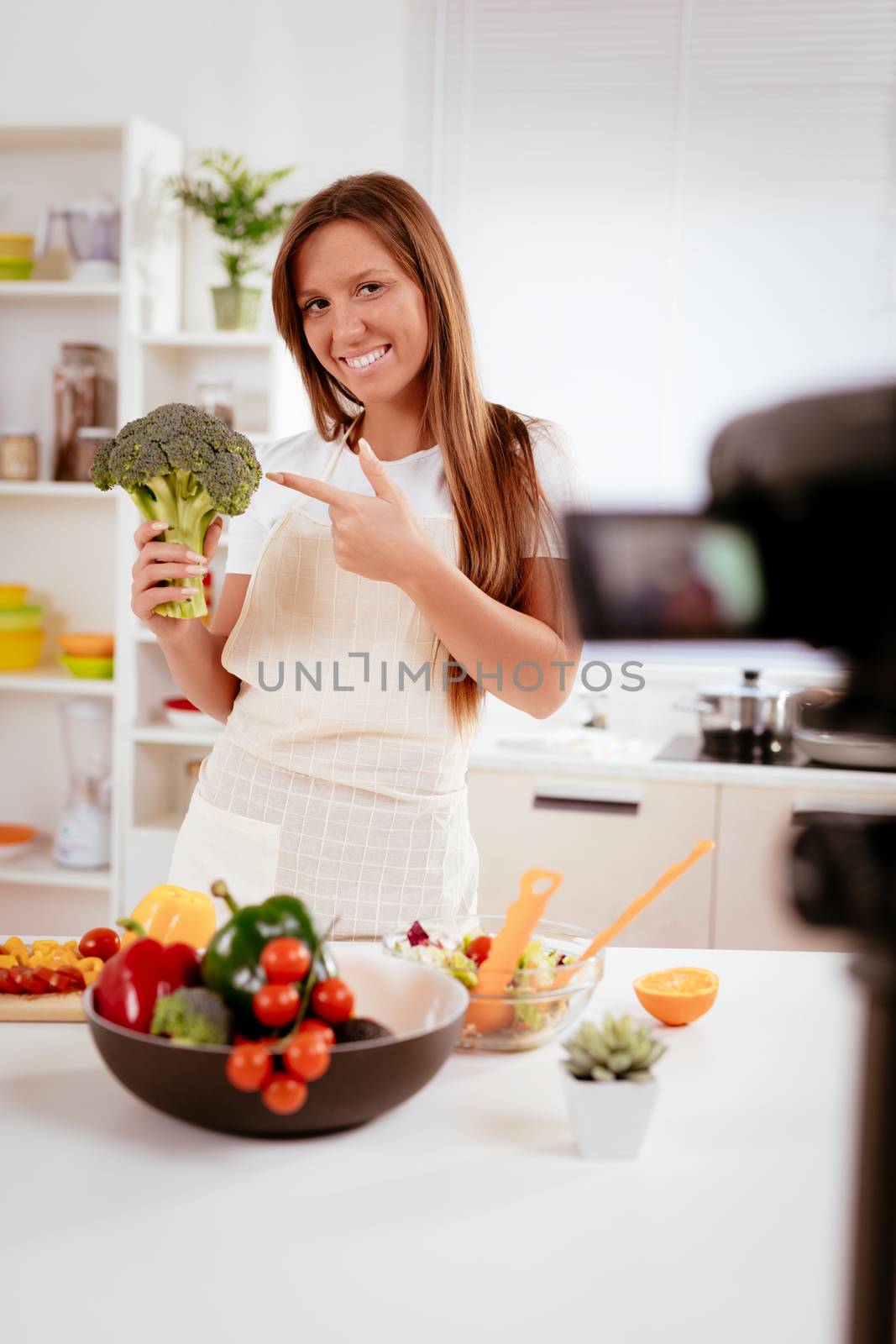 Beautiful young woman filming her blog broadcast about healthy food at the home.