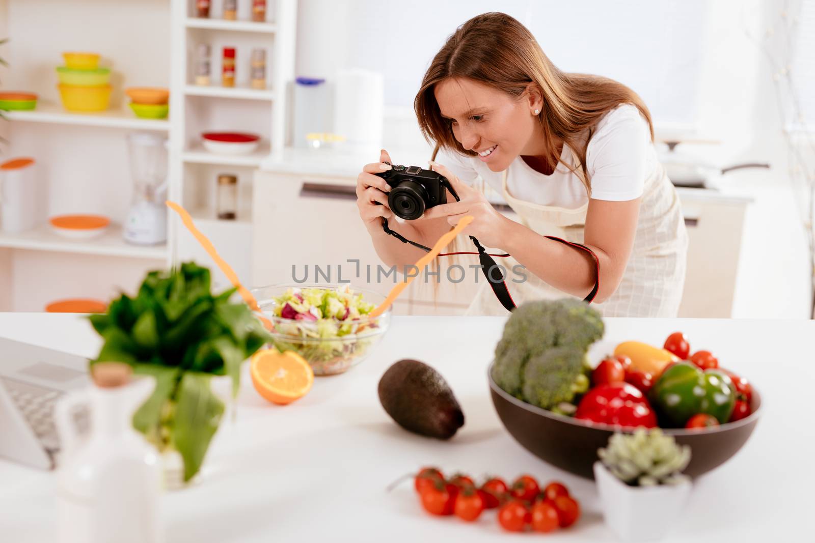 Beautiful young woman taking photo of healthy salad with digital photo camera for her blog.