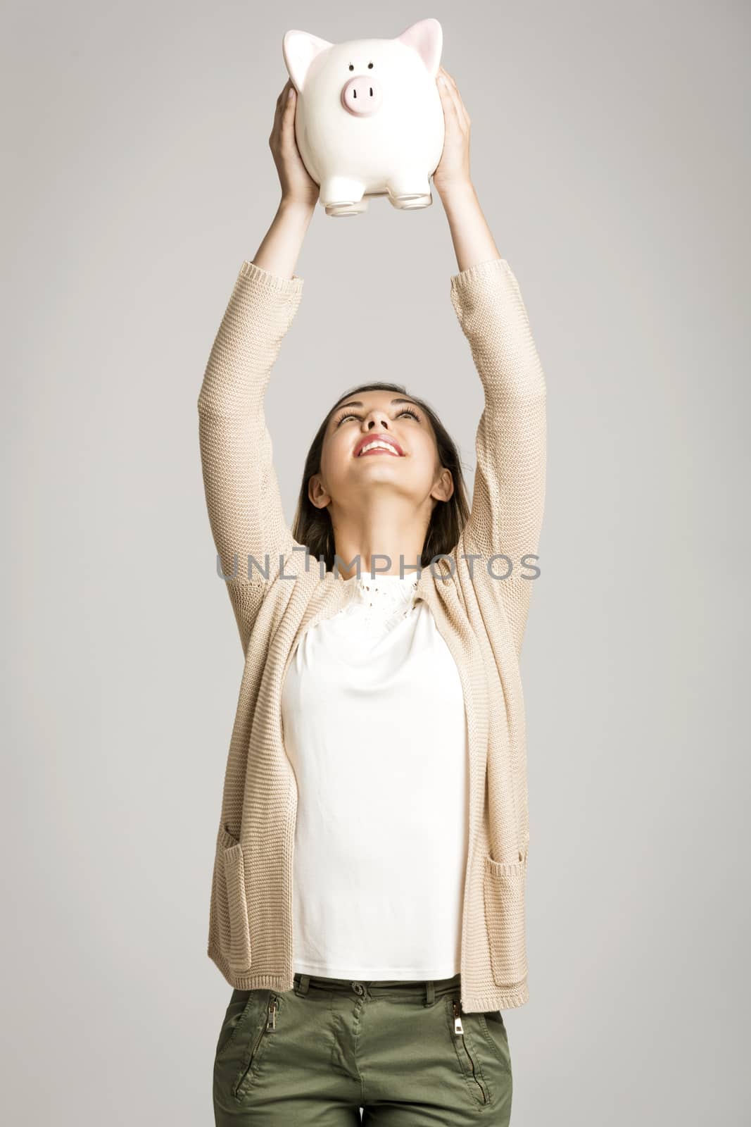 Beautiful and happy woman with arms high holding a piggy bank