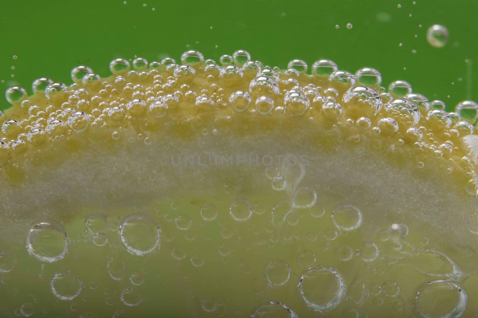 Slice Of Lemon In Mineral Water On Green Background