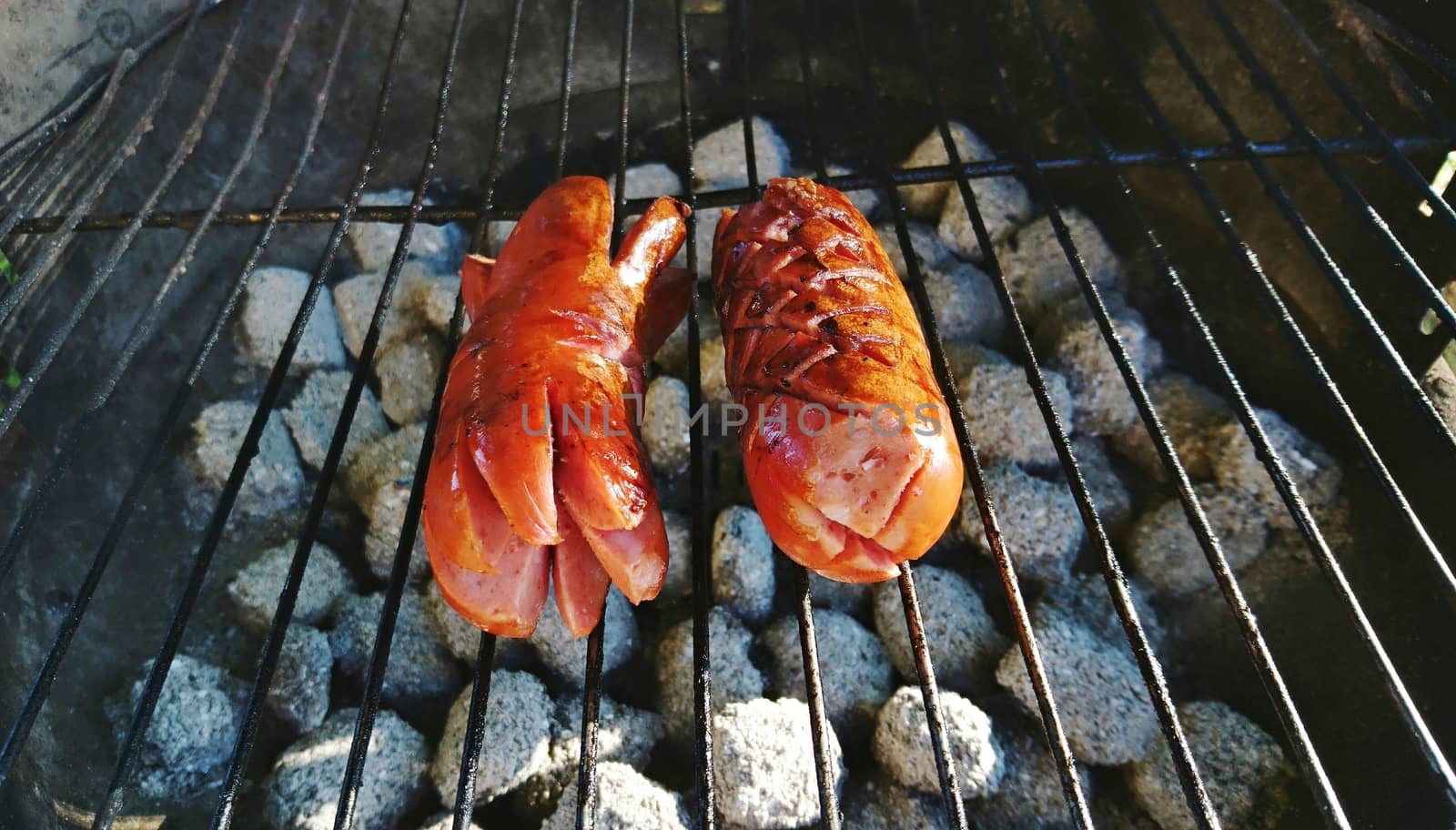 Grilling of a two sausages on a grill. BBQ party.