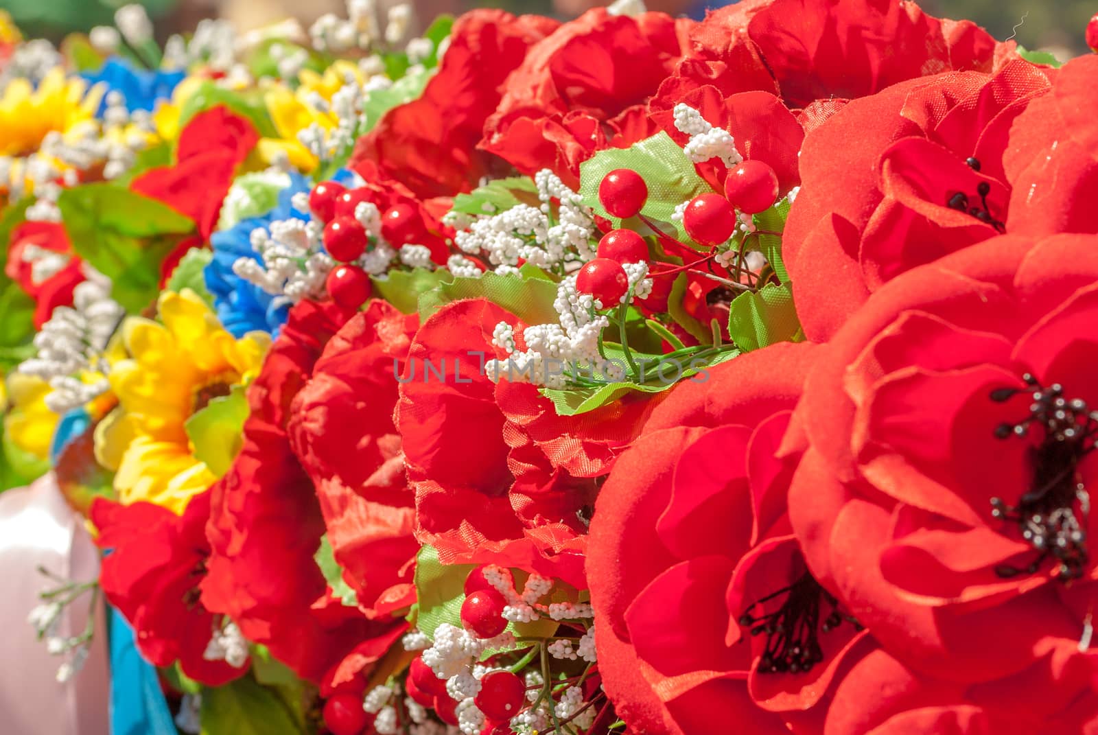 a lot of homemade artificial colored flowers in a beautiful sunny day