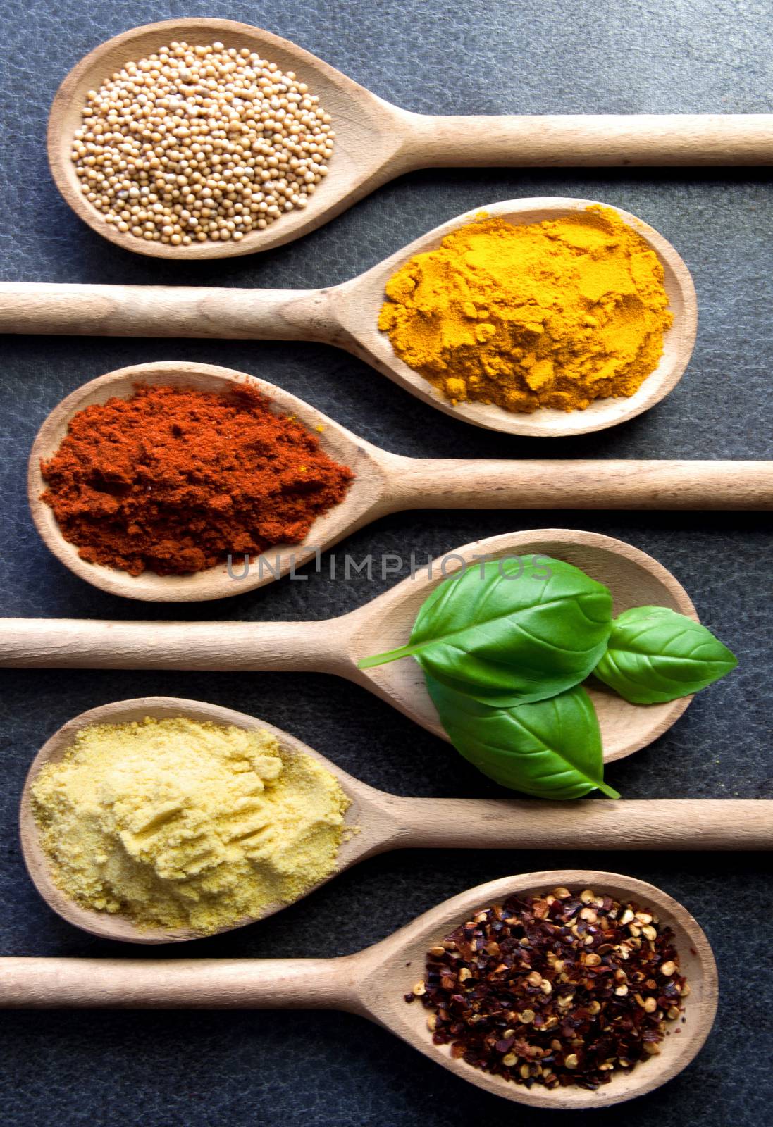 Closeup of assorted herbs and spices in wooden spoons 