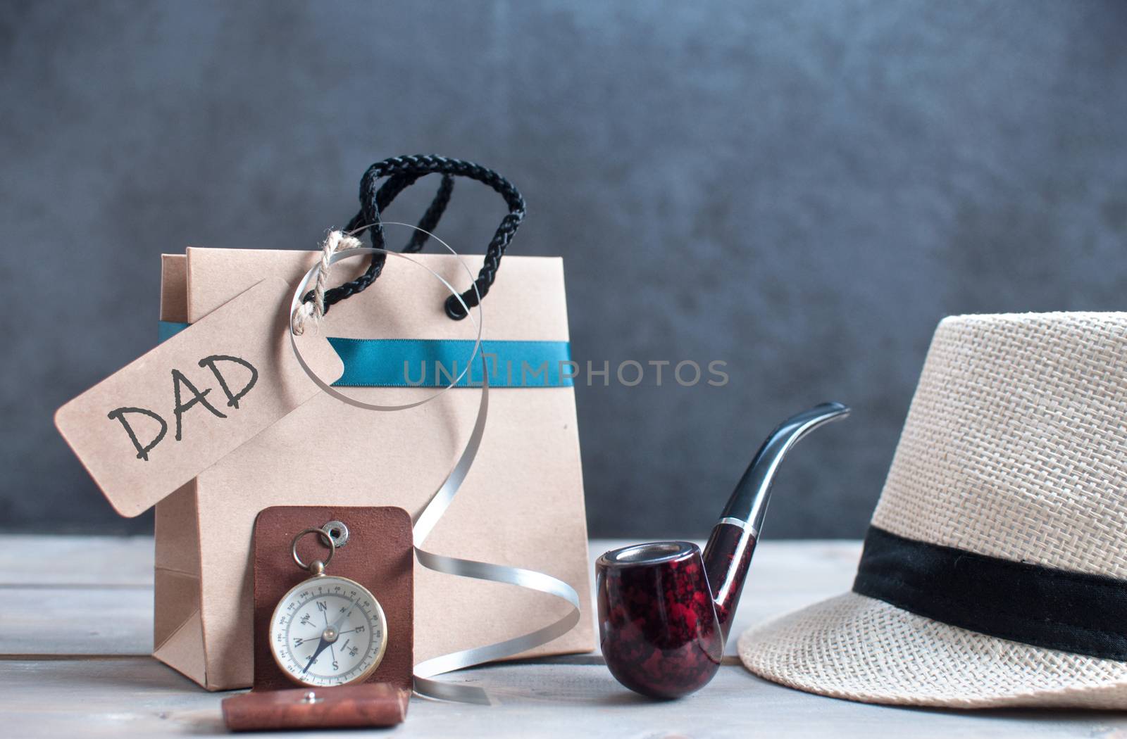 Gift bag with blank label alongside hat, pipe and compass