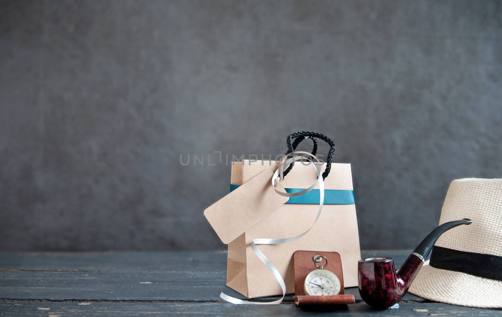 Gift bag with blank label alongside hat, pipe and compass