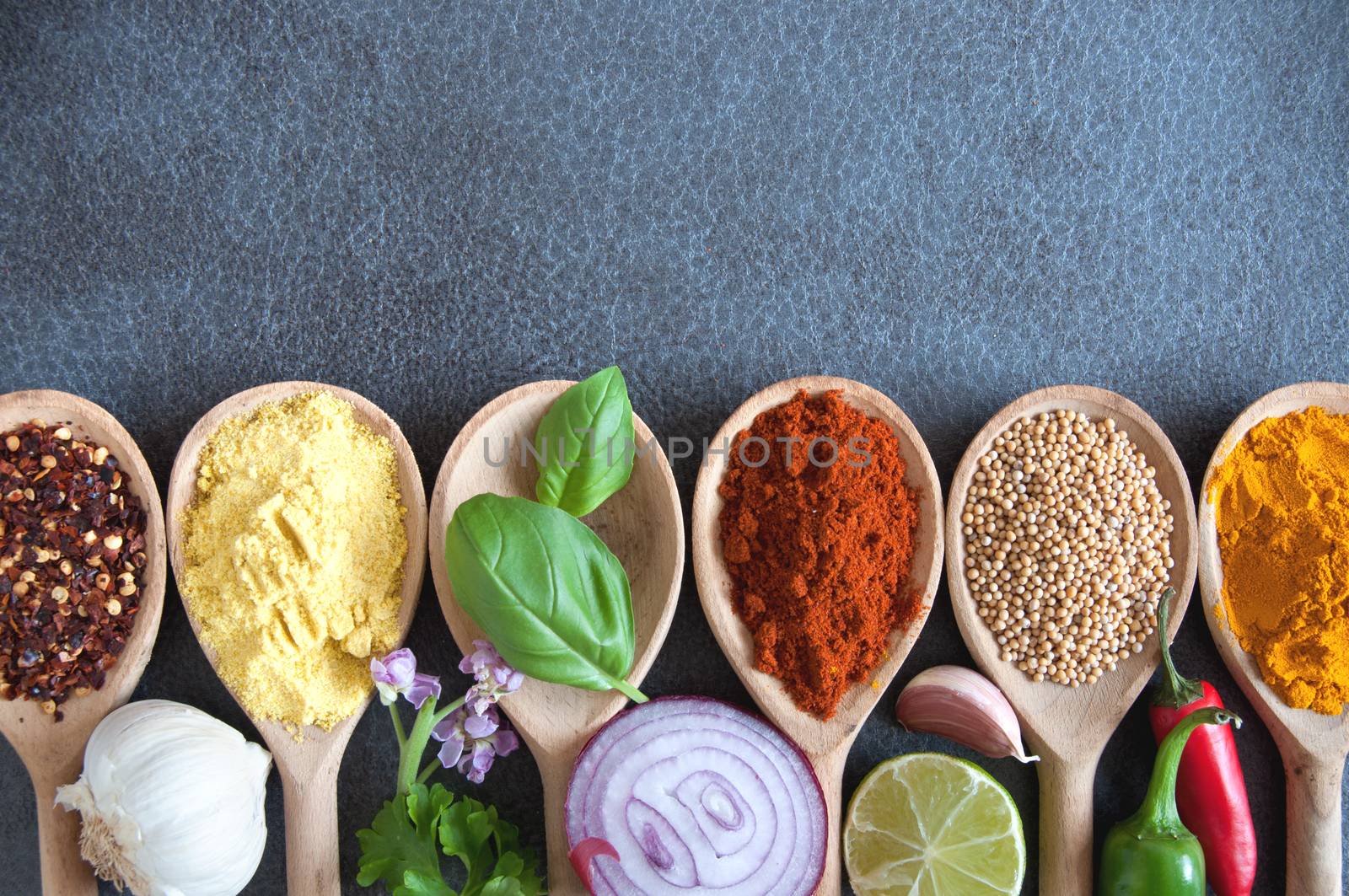 Fresh herbs and spices in wooden spoons with background space 