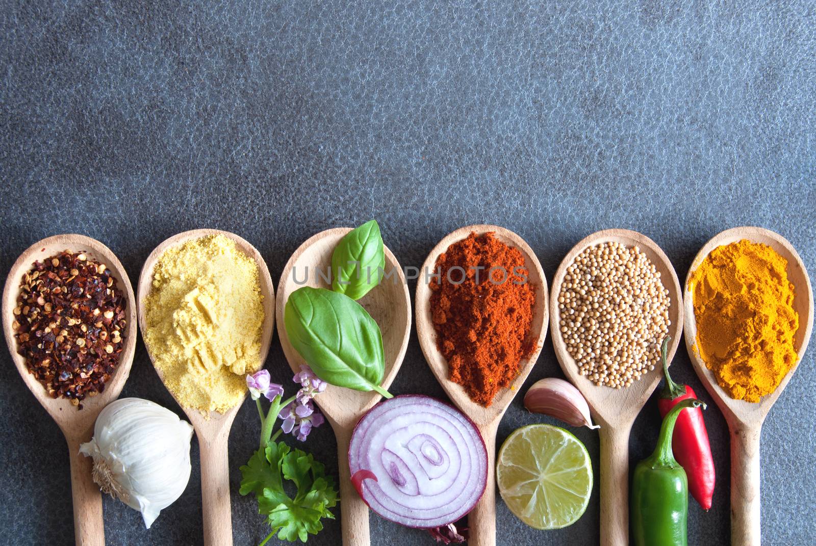 Herbs and spices in wooden spoons border with space