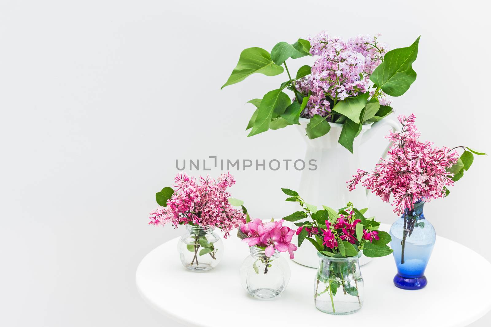 Bouquets of pink and purple spring flowers on a white table.