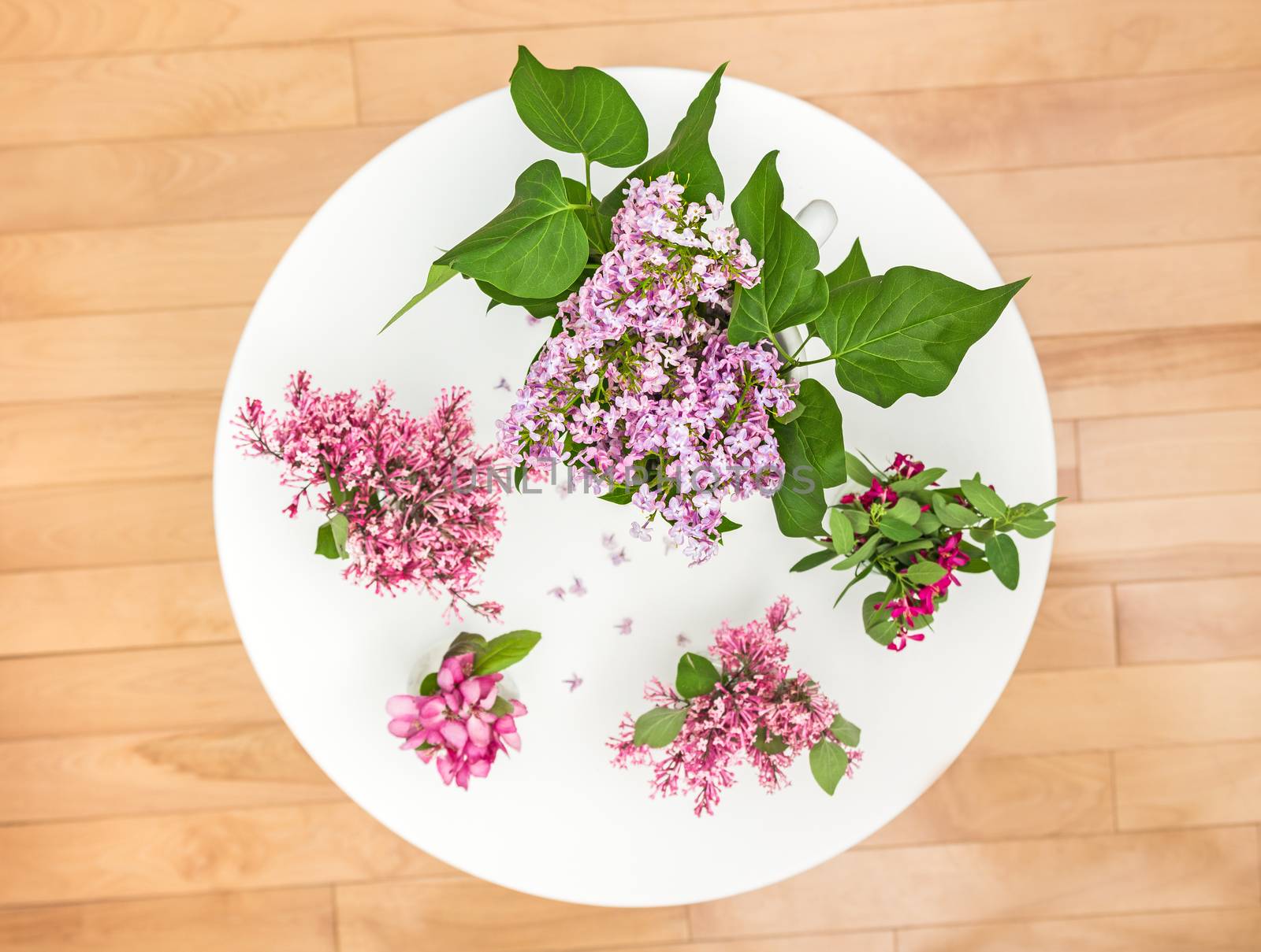 Bouquets of spring flowers on a white round table. View from top.