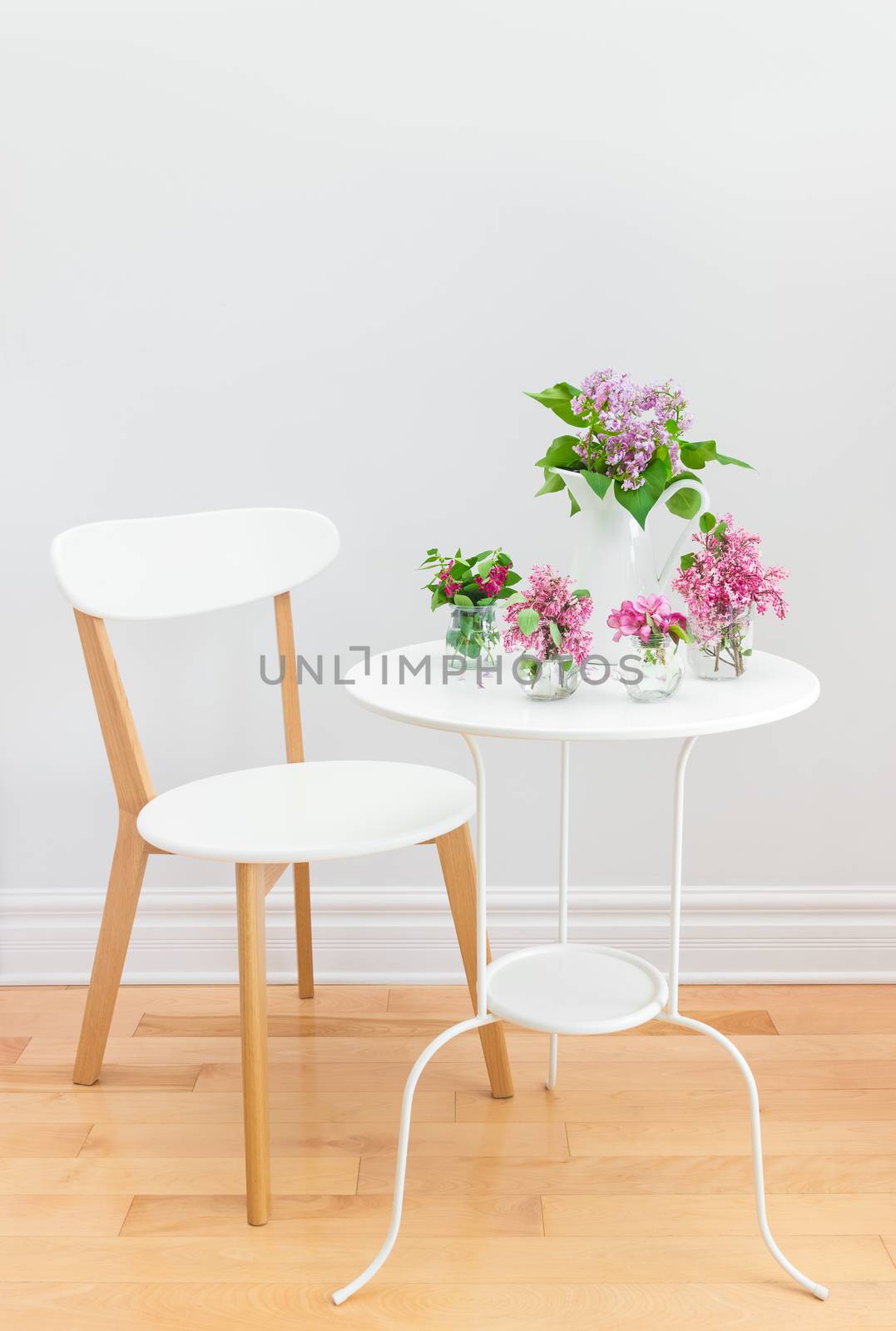 Elegant interior with white table and chair, decorated with bouquets of spring flowers.