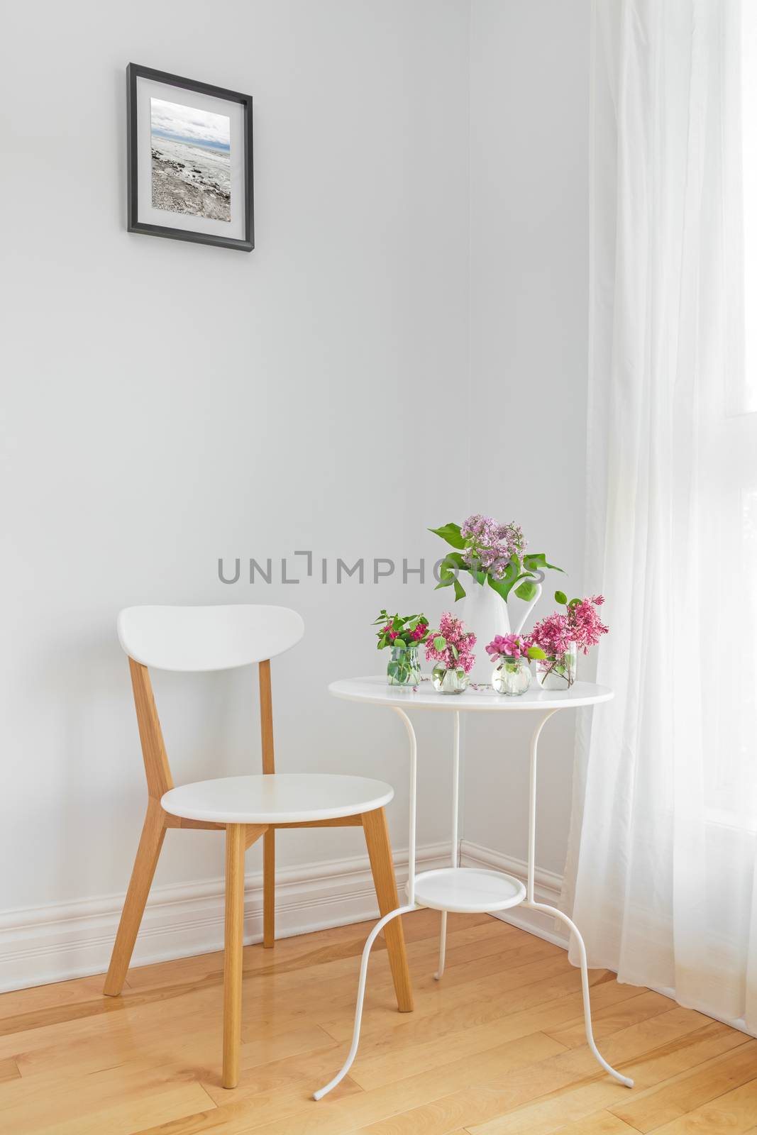 White interior with modern furniture and spring flowers. Elegant home decor.