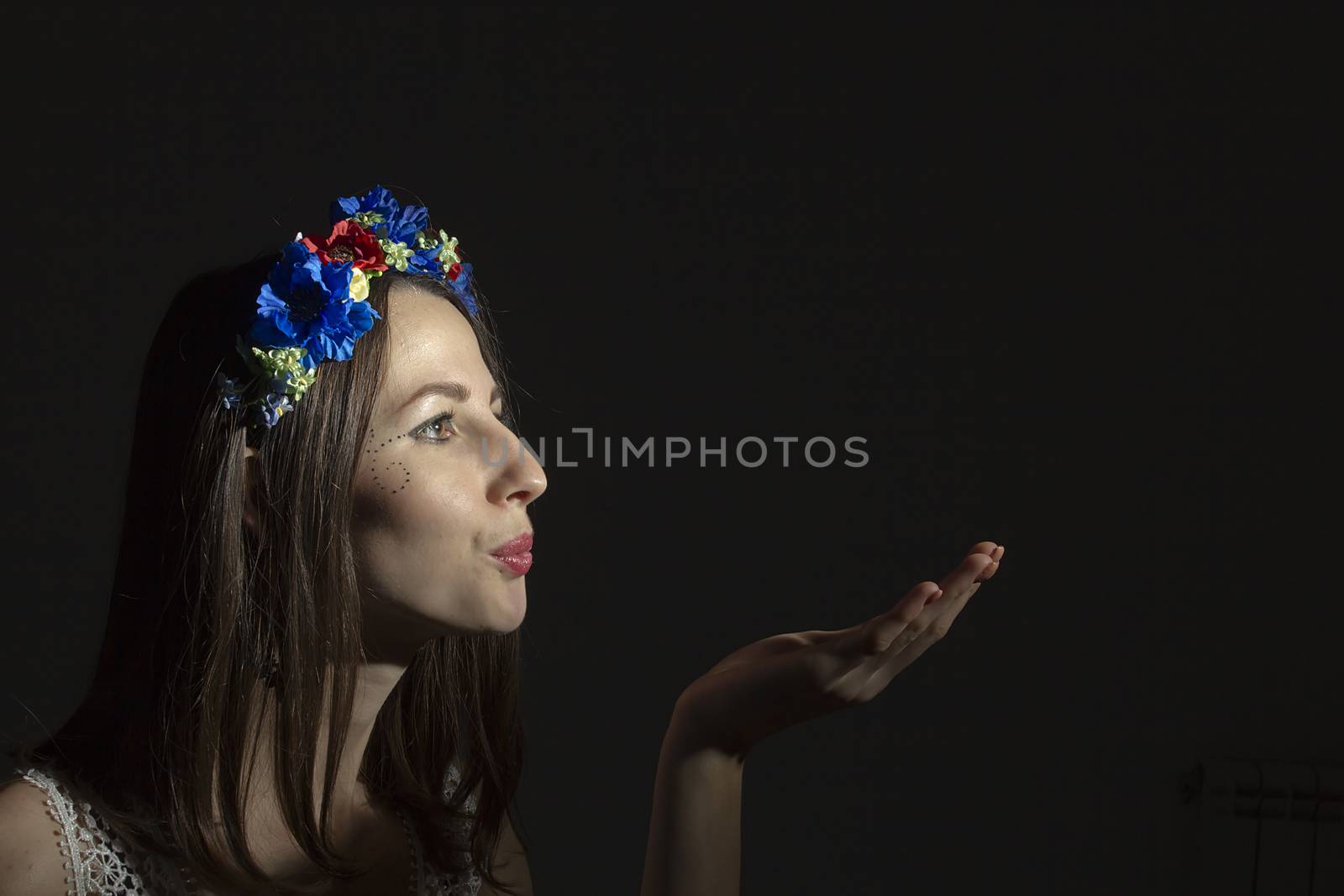 Portrait of a young woman in a wreath of flowers on a black background