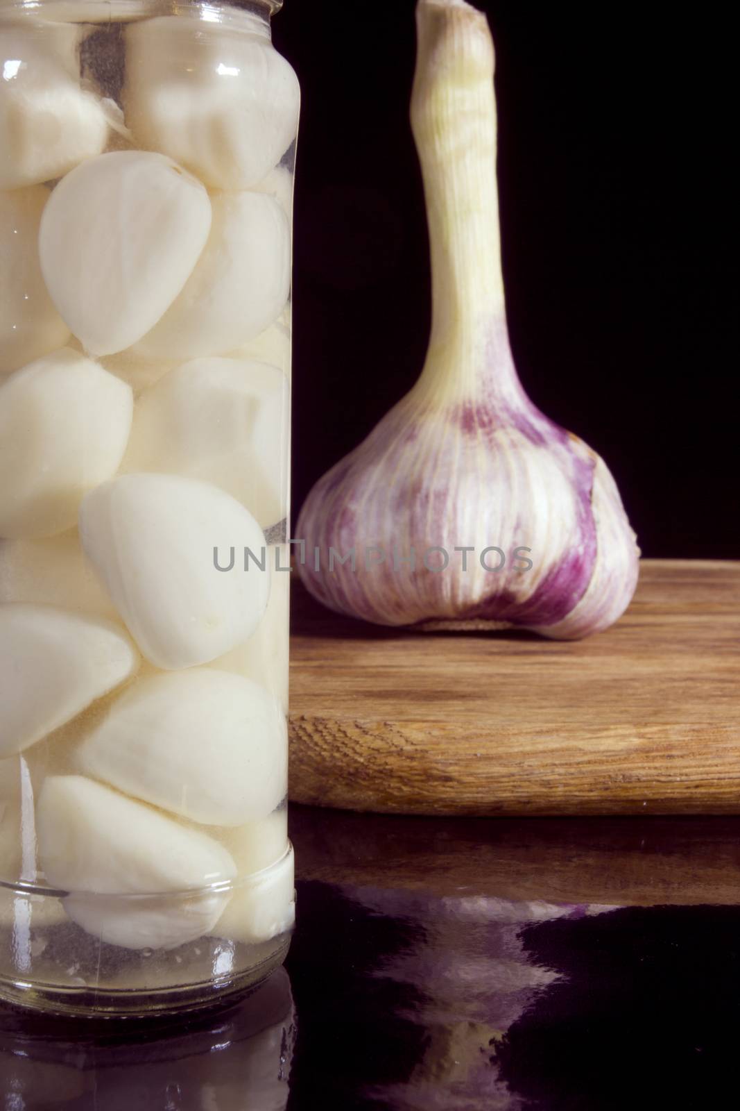 Marinated and fresh garlic with a grater on a dark background