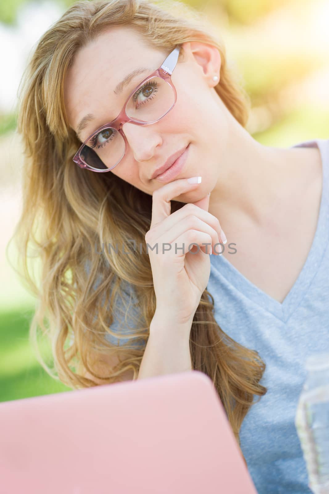 Young Adult Woman Wearing Glasses Outdoors Using Her Laptop. by Feverpitched