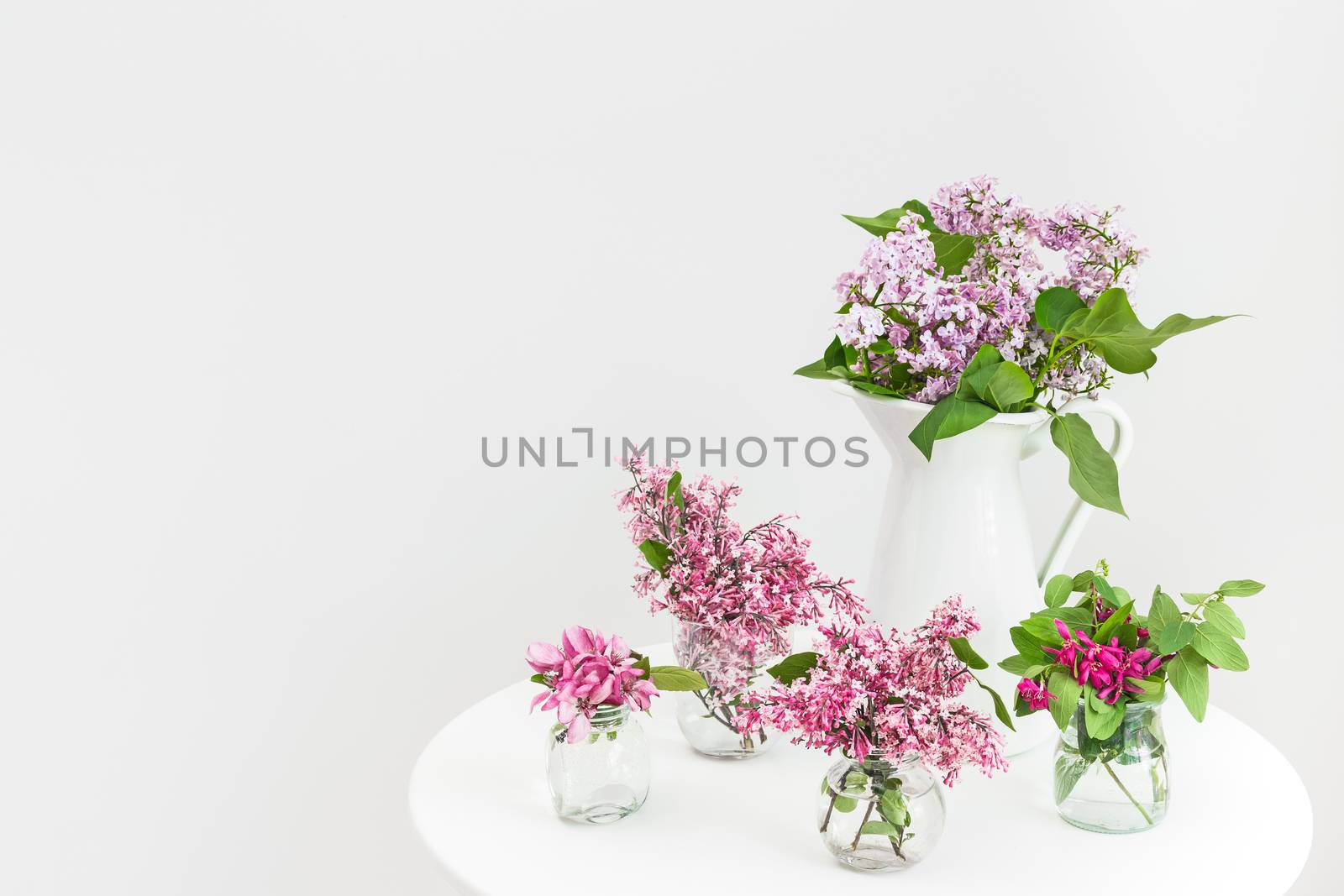 Vases with pink and purple blooming spring flowers on a round table.