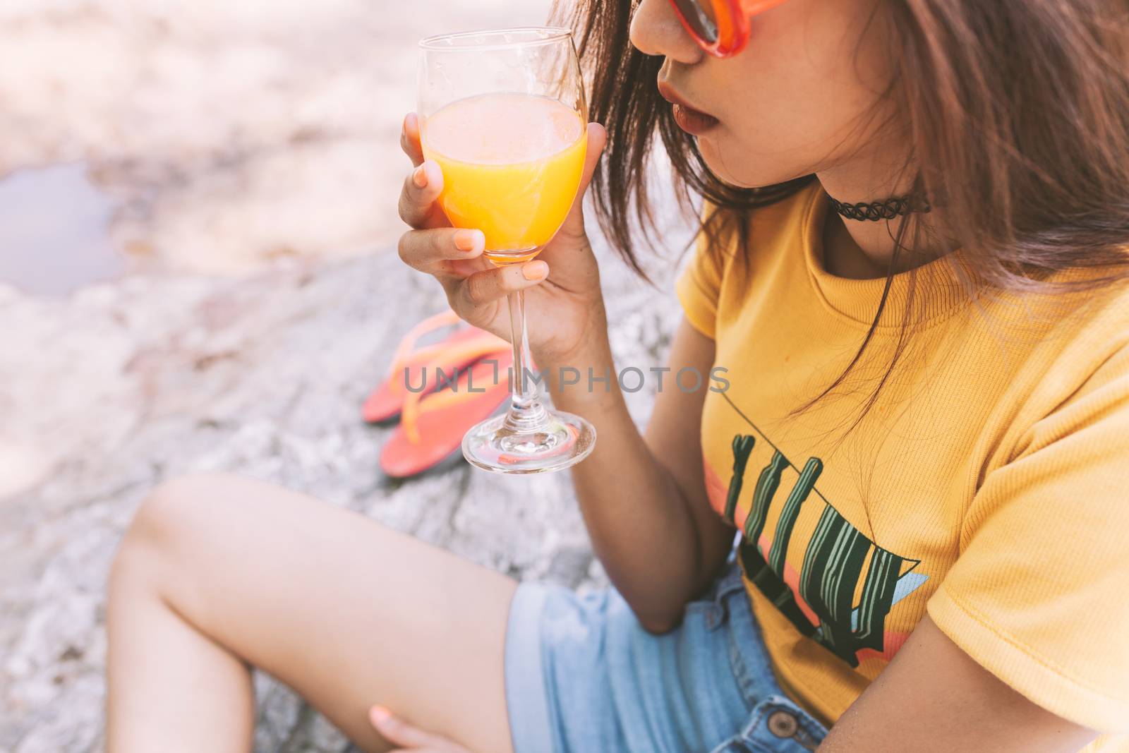 Woman drinking iced drinks outdoors with sand by the sea by nopparats