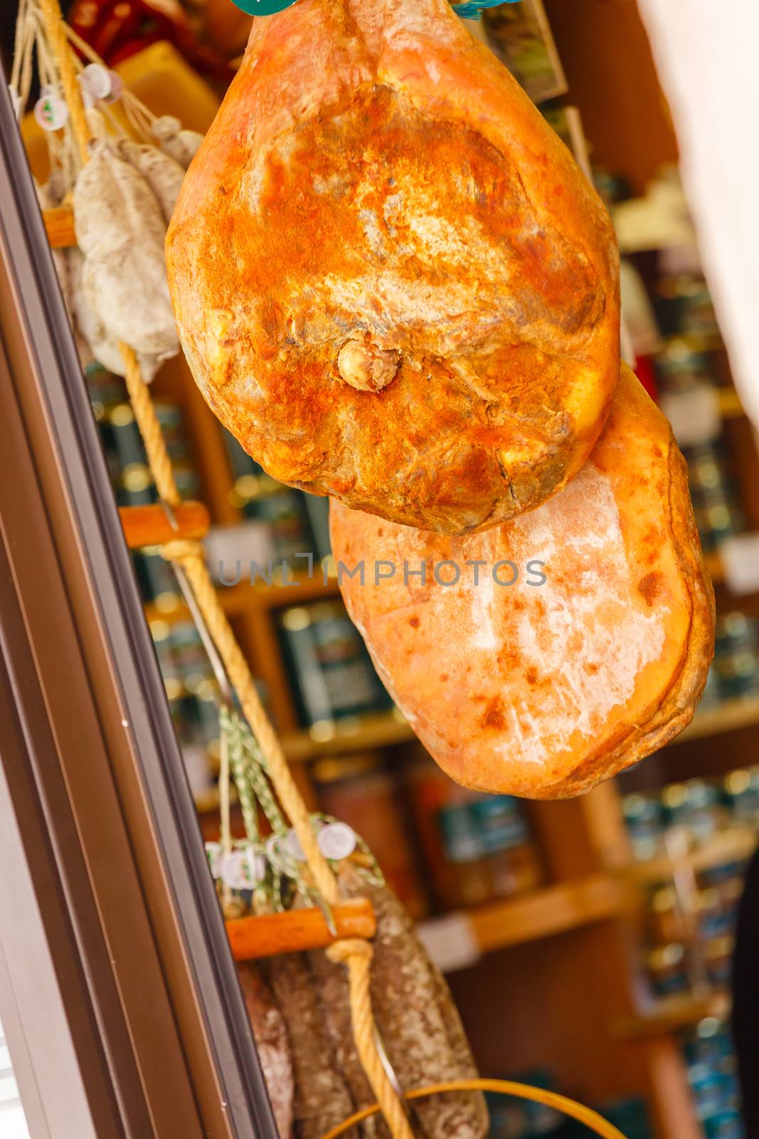 Jamon serrano hung at the entrance of a gourmet shop by pixinoo