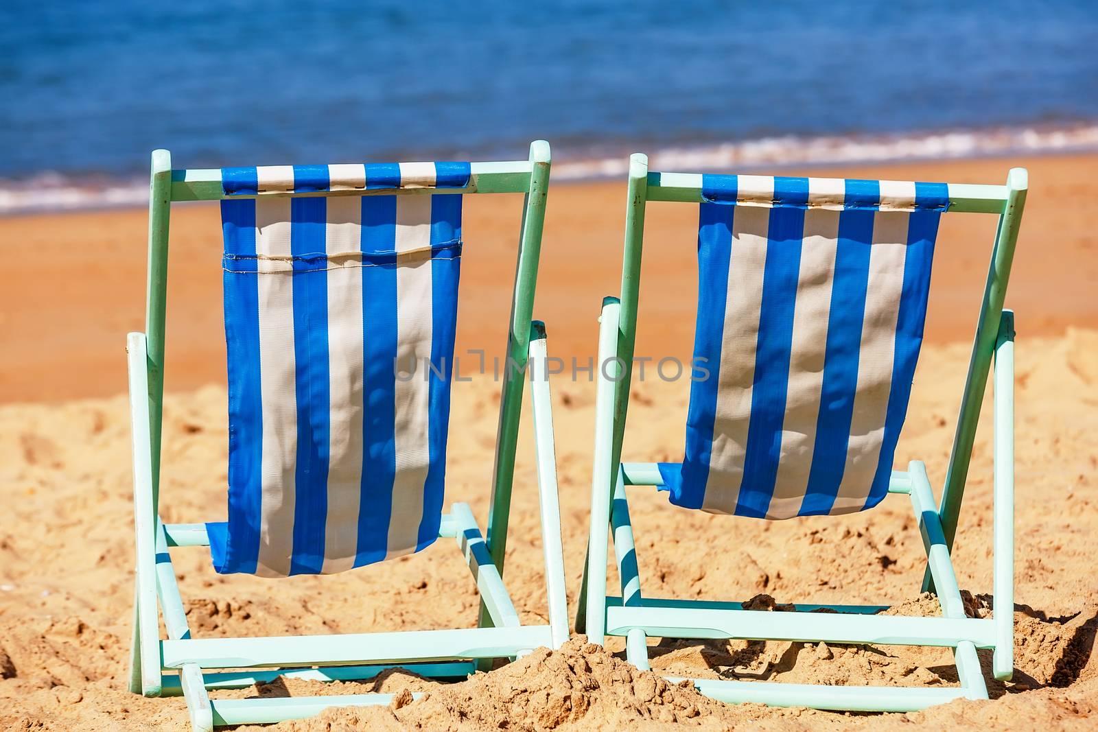 Two empty deckchairs facing the sea by pixinoo