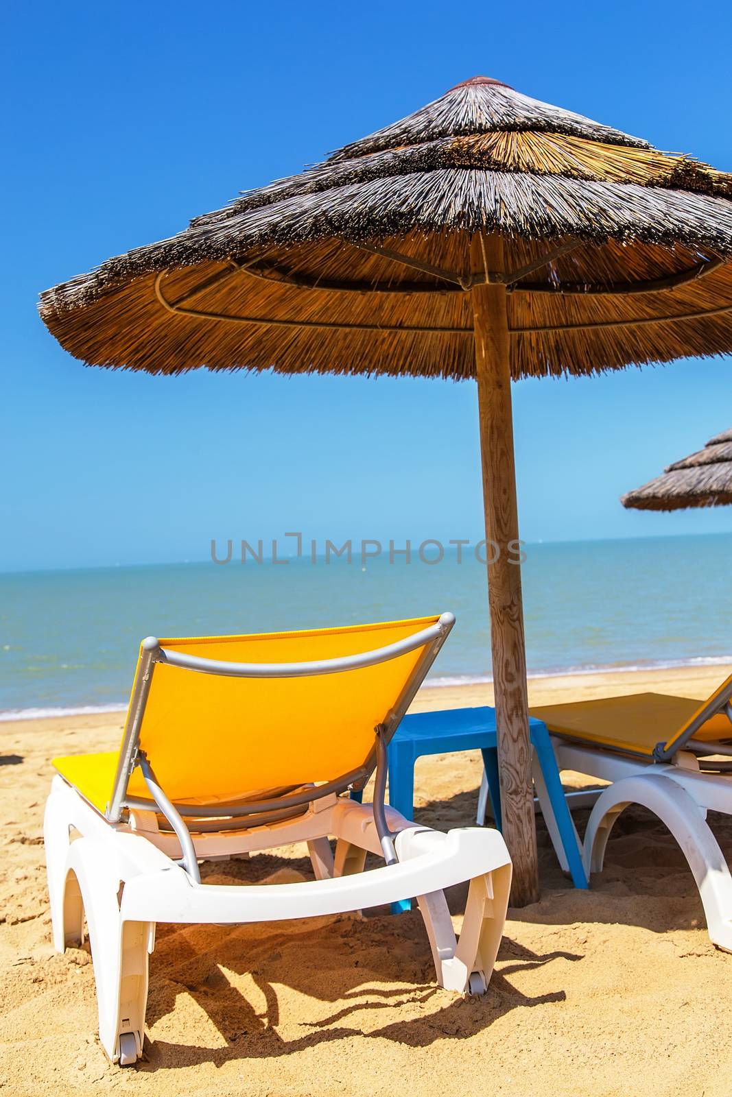 Beach umbrellas and deckchair on the tropical beach by pixinoo