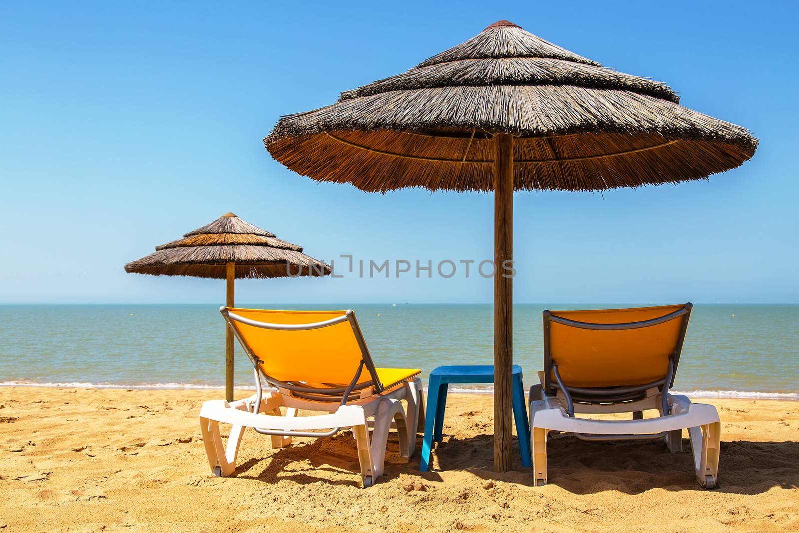 Beach umbrellas and deckchair on the tropical beach by pixinoo