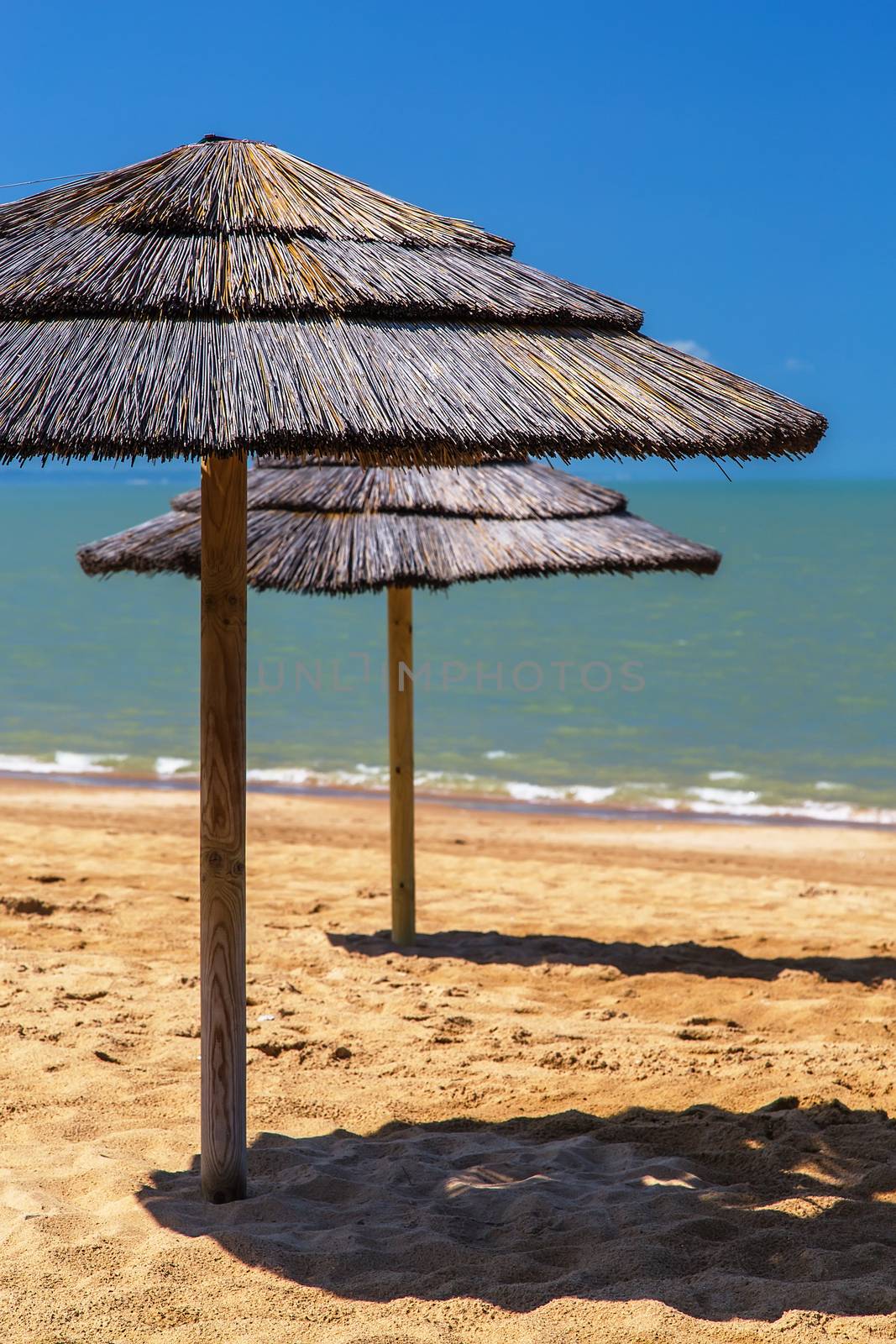 straw beach umbrella with blue sky by pixinoo