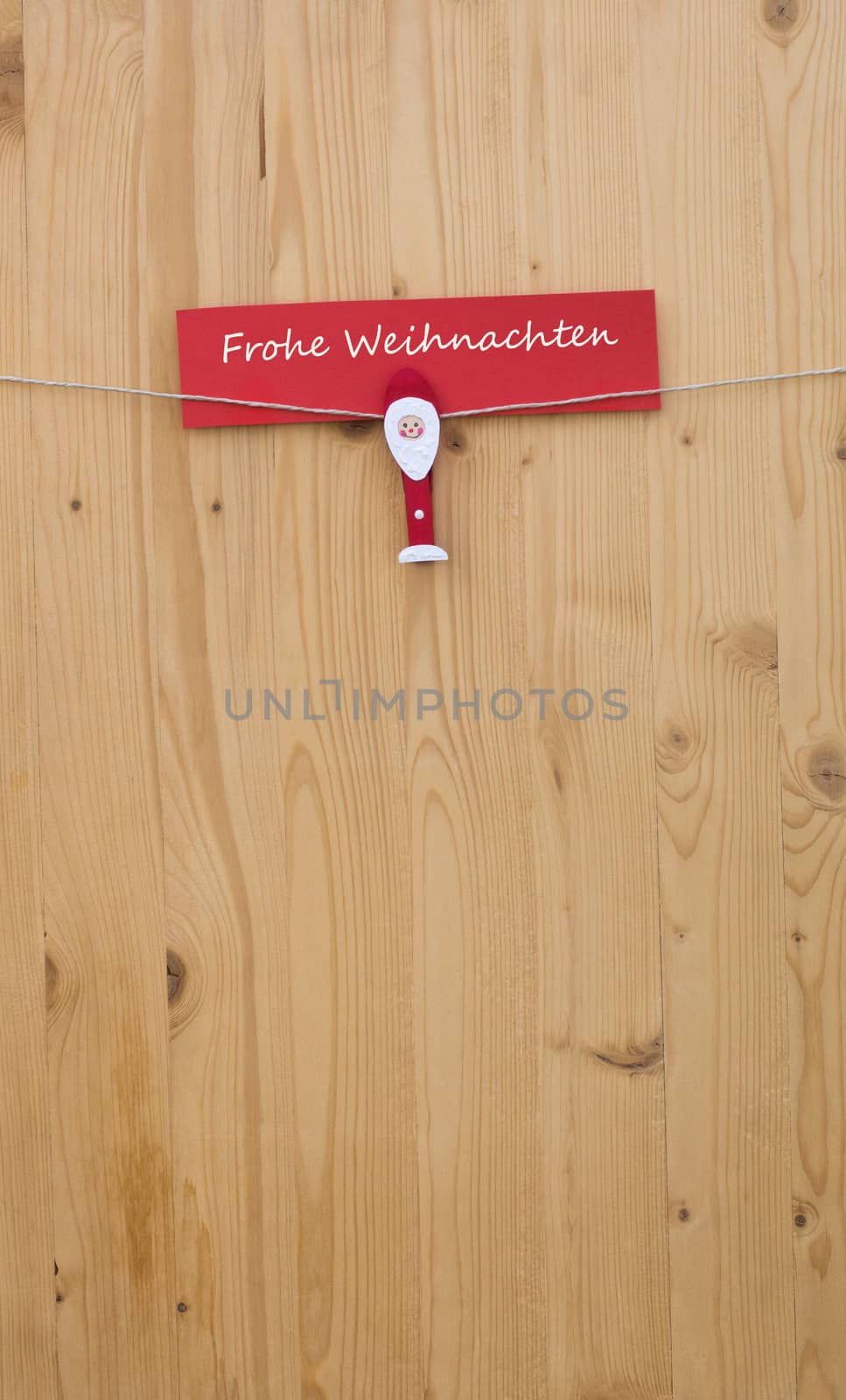 One christmas man with clothes pegs on a cord on wood and german text for merry christmas