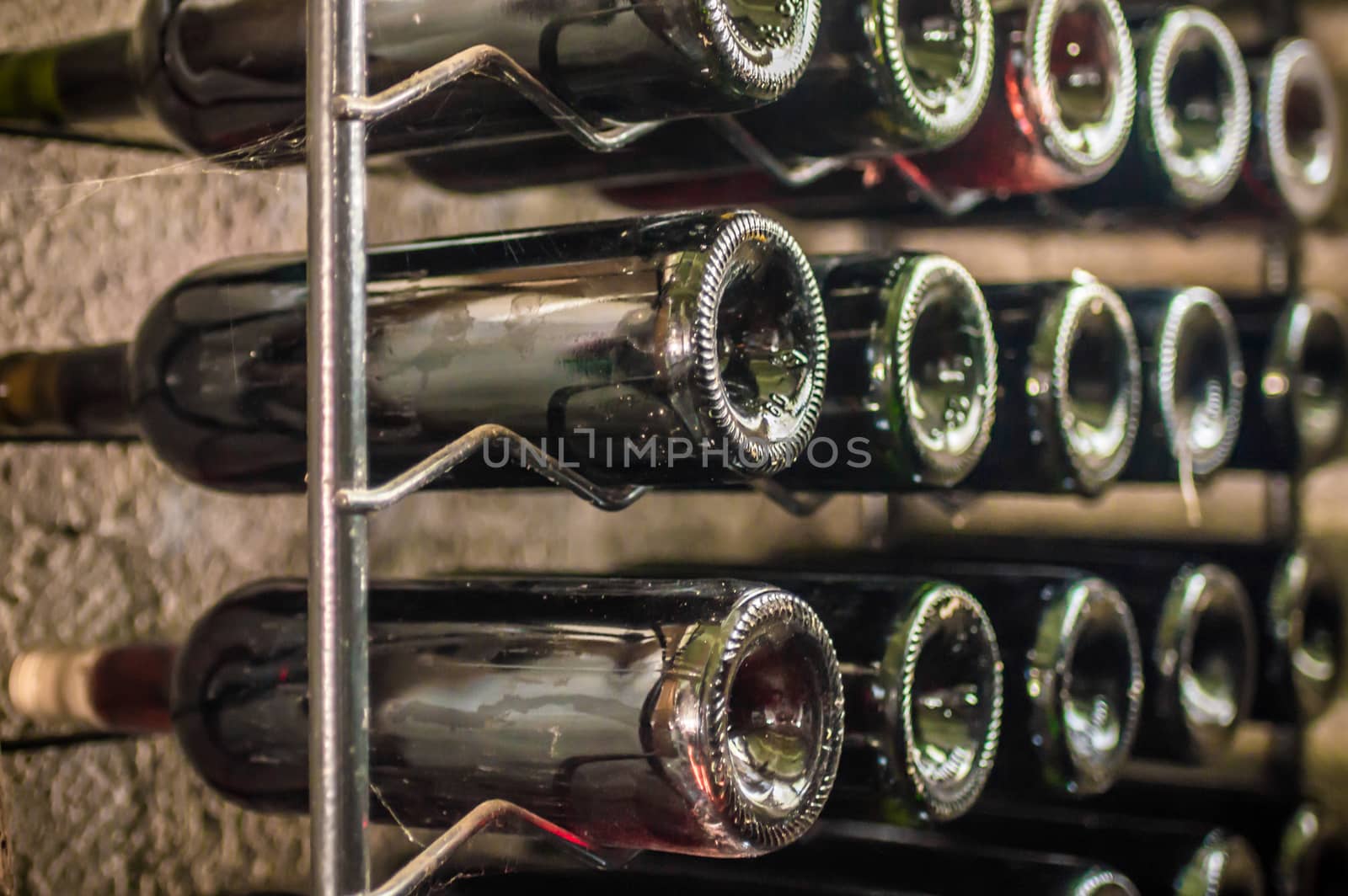 bottles of red wine lying on an iron shelf