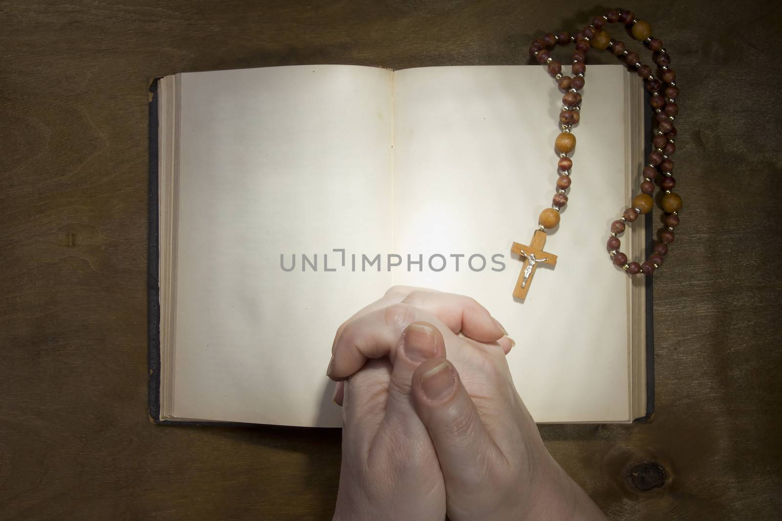 Female hands with rosary and an old book