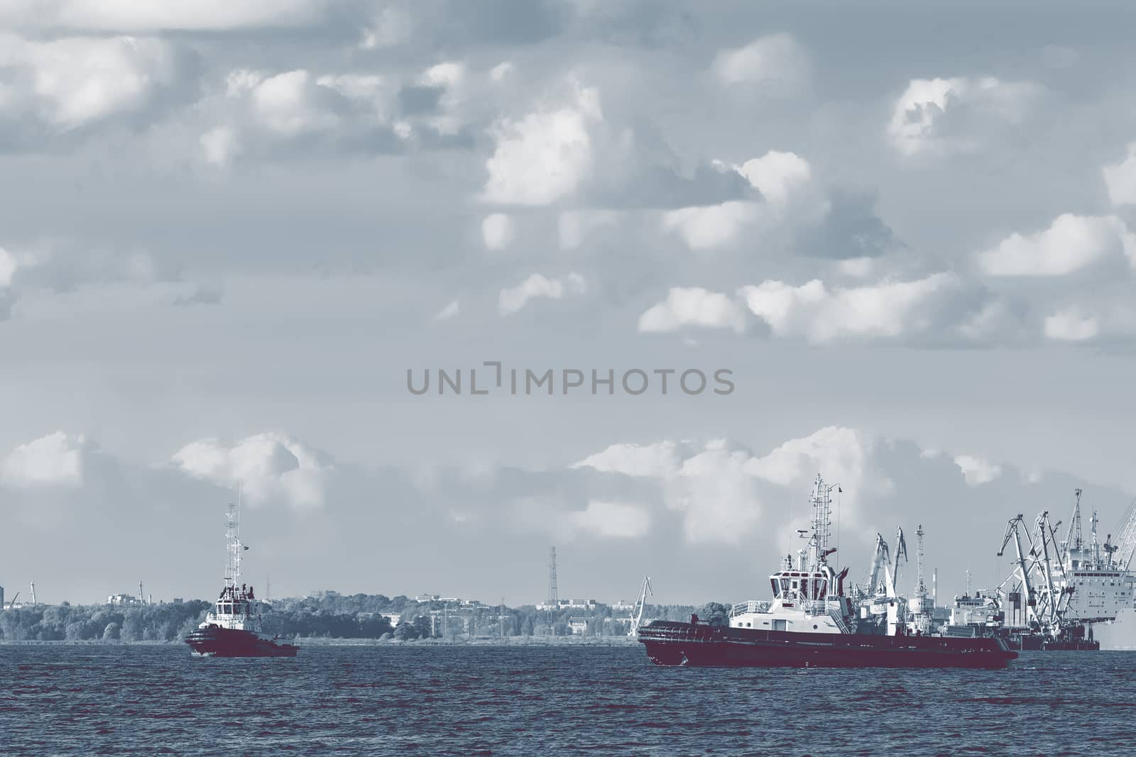 Two tug ships are accepting cargo vessel at Daugava river