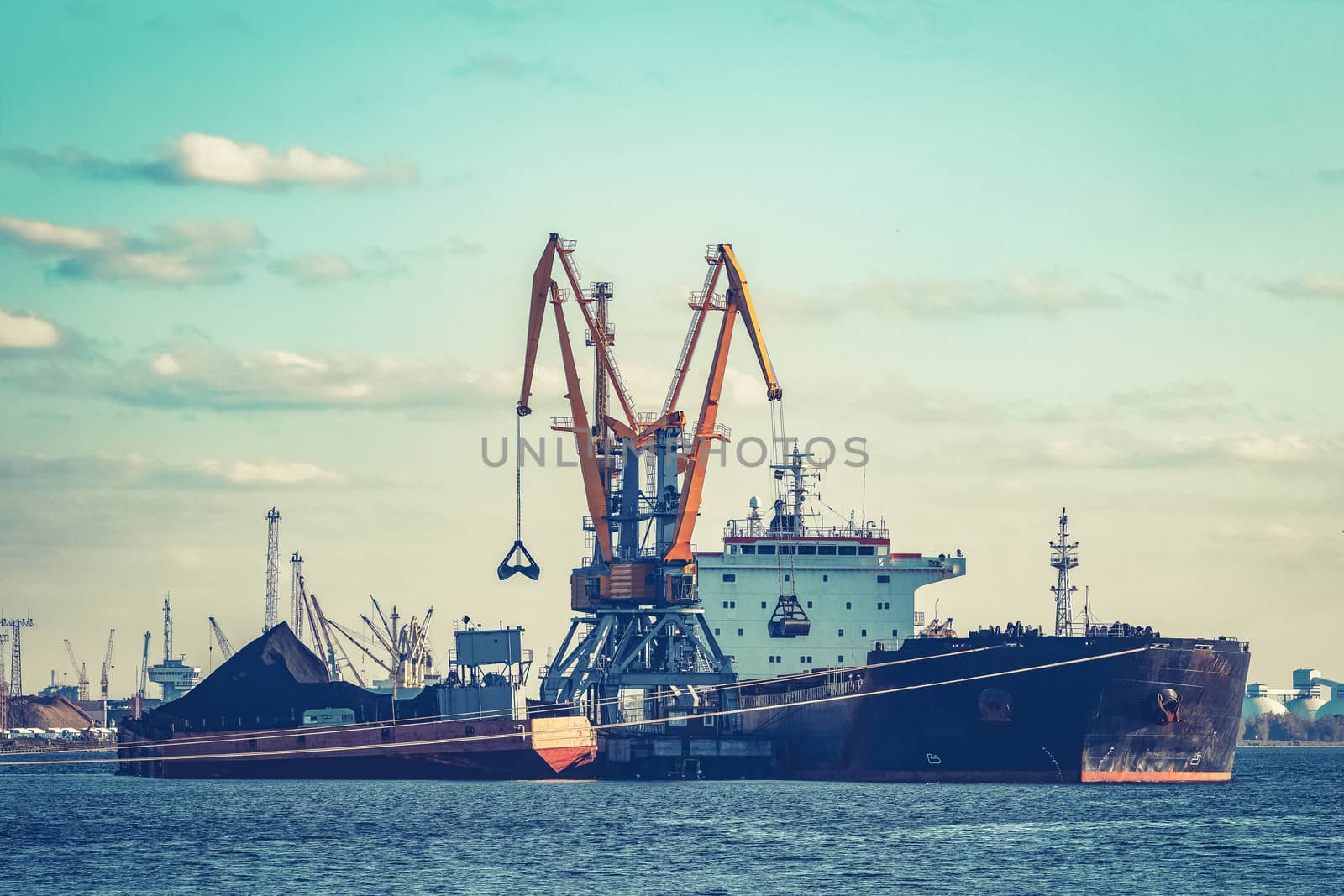 Black cargo ship loading with a coal at the port