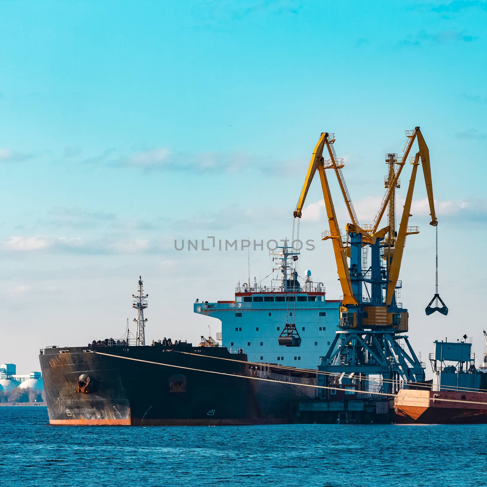 Black cargo ship loading with a coal at the port