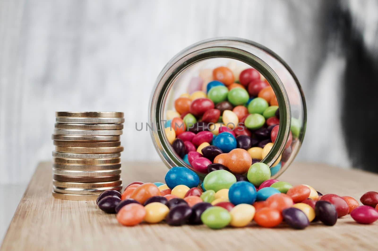Money jar and colorful sweets on the wooden board in the kitchen.