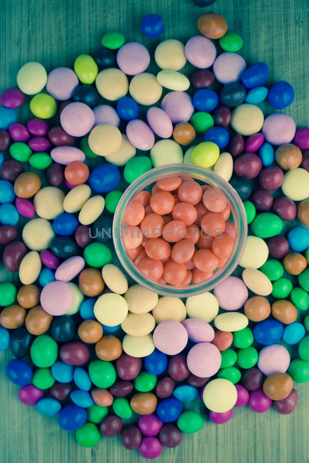 Tasty orange jelly sweets in glass jar on the wooden board.