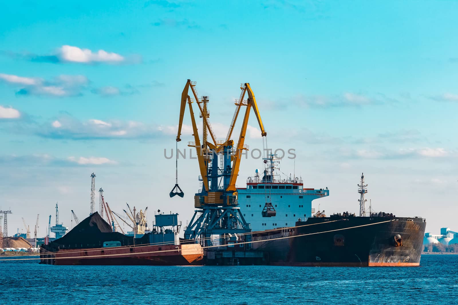 Black cargo ship loading with a coal at the port