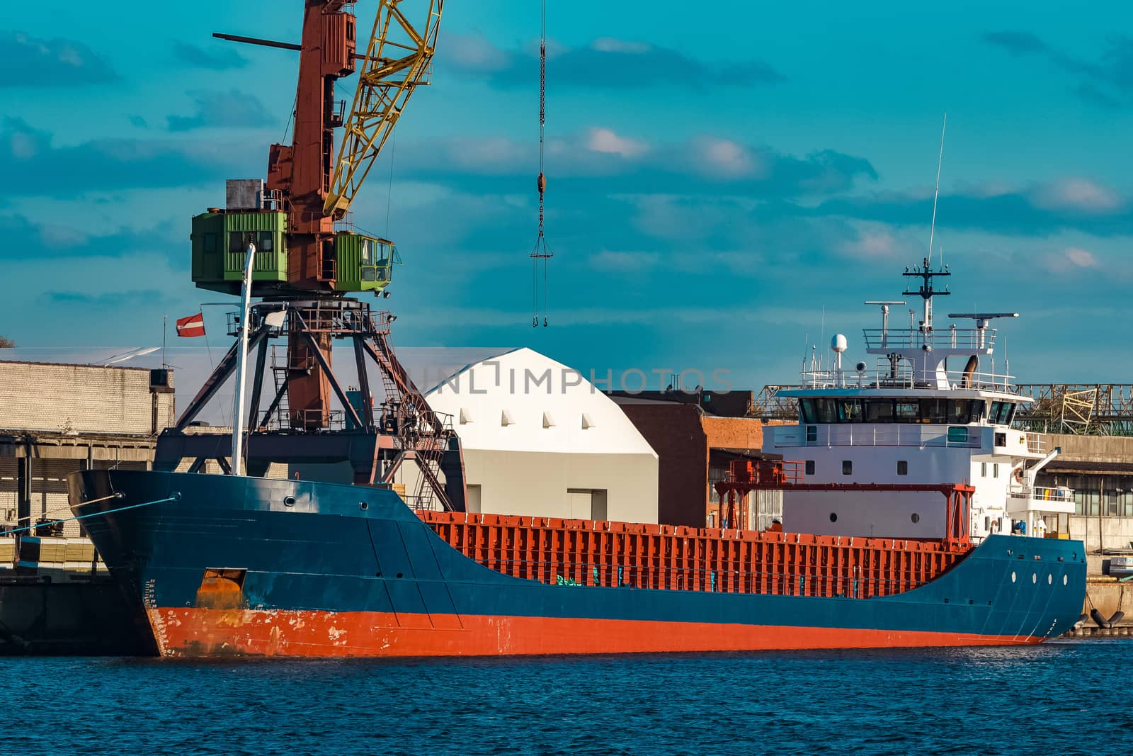 Blue cargo ship moored and loading at the port